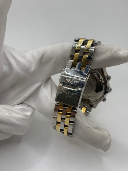 Montre Breitling Chronomat B13050.1 en or et acier avec boîtier de 39 mm, cadran blanc à chiffres arabes, verre saphir et mouvement automatique Breitling 13 basé sur l'ETA Valjoux 7750. Ce chronographe est équipé d'un bracelet en or et acier avec boucle déployante d'origine. Révisée, en excellent état et garantie 1 an, cette montre de luxe suisse allie élégance intemporelle, précision horlogère et finitions haut de gamme.