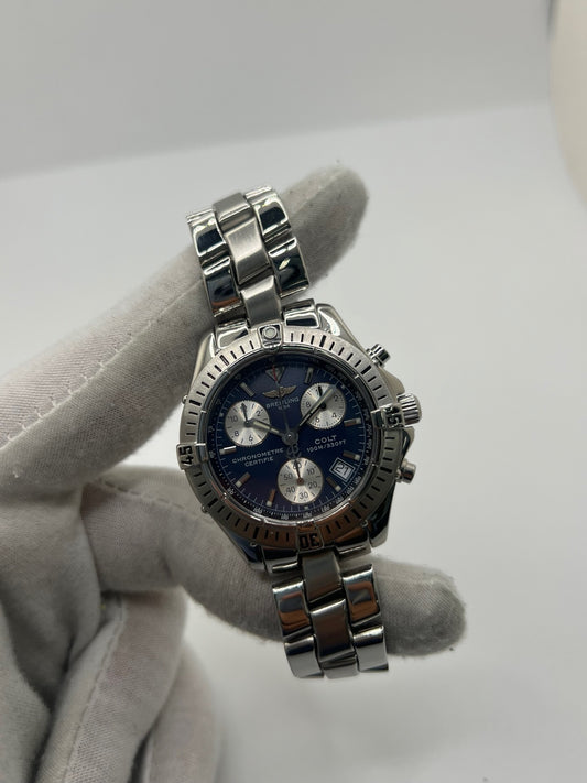 Montre Breitling Colt Chronograph A73350 en acier pour homme ou unisexe, équipée d’un mouvement quartz et d’un boîtier de 38 mm. Ce chronographe d’occasion en très bon état présente un cadran bleu sans chiffres, un verre saphir, une étanchéité de 10 ATM et une fonction date. Son bracelet en acier avec boucle déployante apporte confort et robustesse. Cette Breitling Colt Chronograph séduit par son style sportif, précis et intemporel, idéal pour les amateurs de montres de luxe.