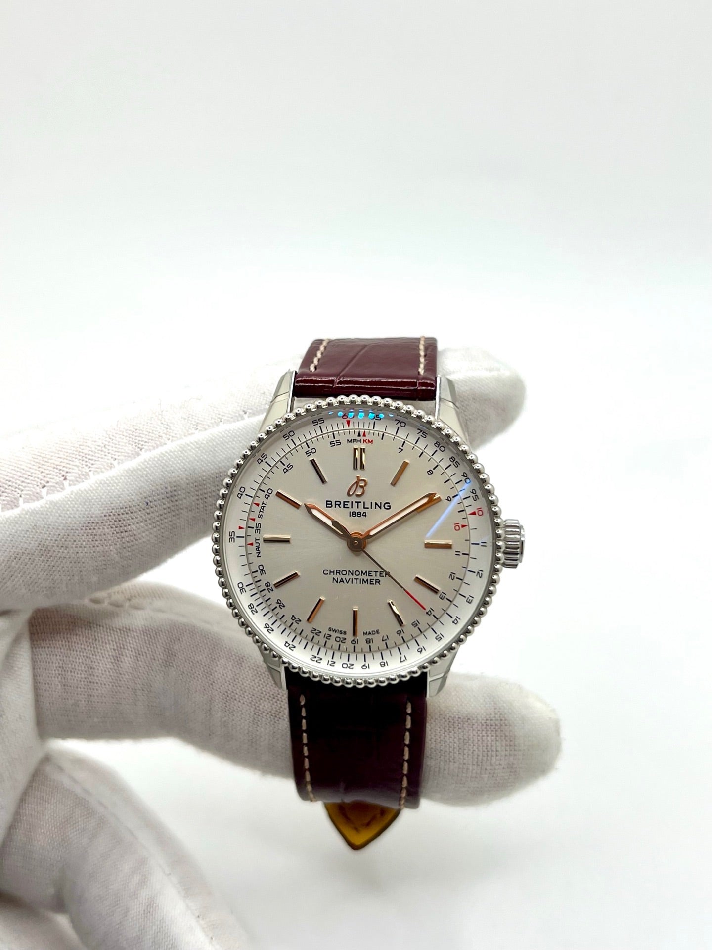 Montre Breitling Navitimer A17327211G1P1 pour femme, modèle automatique en acier de 36 mm avec cadran argent sans chiffres et verre saphir. Cette montre de luxe dispose du calibre Breitling 17 avec une réserve de marche de 38 heures. Elle est équipée d’un bracelet en cuir bordeaux avec boucle déployante en acier. Montre étanche à 3 ATM, état neuf, jamais portée, sans coffret ni papiers d’origine.