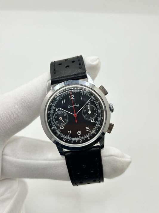 Montre Breitling Premier Chronograph 782 datant d’environ 1950, équipée d’un mouvement à remontage manuel et du calibre Venus 175. Son boîtier en acier de 38 mm accueille un cadran noir à chiffres arabes, protégé par un verre Plexiglas. Cette montre Breitling est montée sur un bracelet noir en cuir avec boucle ardillon en acier. Dotée d’une fonction chronographe, elle séduit par son style vintage et son caractère intemporel. En bon état, elle présente des traces d’usure visibles.