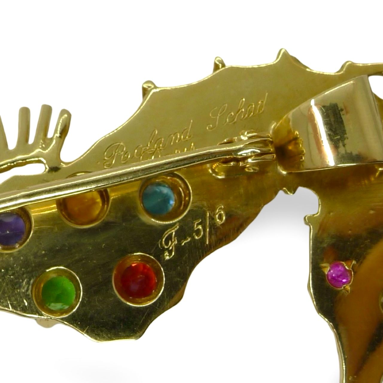 Laissez-vous séduire par cette broche hippocampe en or jaune et pierres fines, une création élégante signée Roland Schad. Ce bijou raffiné allie originalité et savoir-faire artisanal, idéal pour sublimer votre style avec une touche marine et précieuse.