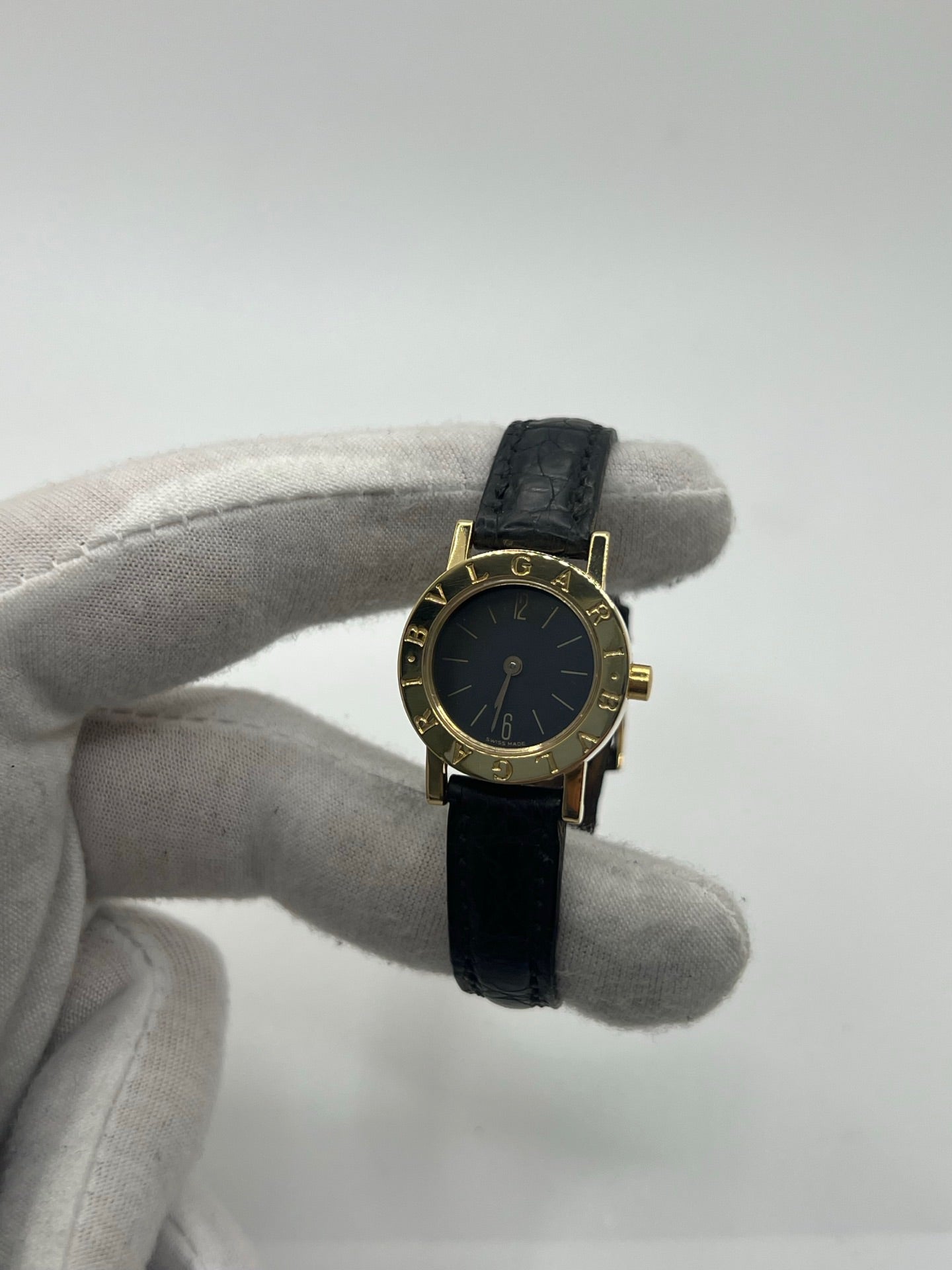 Montre femme Bulgari Bulgari Lady BB 23 GL en or jaune avec boîtier rond de 23 mm, cadran noir élégant et verre saphir. Cette montre de luxe à mouvement quartz est dotée d’un bracelet en cuir noir avec boucle ardillon en or jaune. Modèle emblématique au design intemporel, idéal pour un poignet féminin, alliant raffinement, précision et savoir-faire horloger italien. Parfaite comme montre habillée ou pièce de collection.