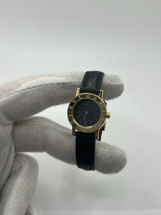Montre femme Bulgari Bulgari Lady BB 23 GL en or jaune avec boîtier rond de 23 mm, cadran noir élégant et verre saphir. Cette montre de luxe à mouvement quartz est dotée d’un bracelet en cuir noir avec boucle ardillon en or jaune. Modèle emblématique au design intemporel, idéal pour un poignet féminin, alliant raffinement, précision et savoir-faire horloger italien. Parfaite comme montre habillée ou pièce de collection.