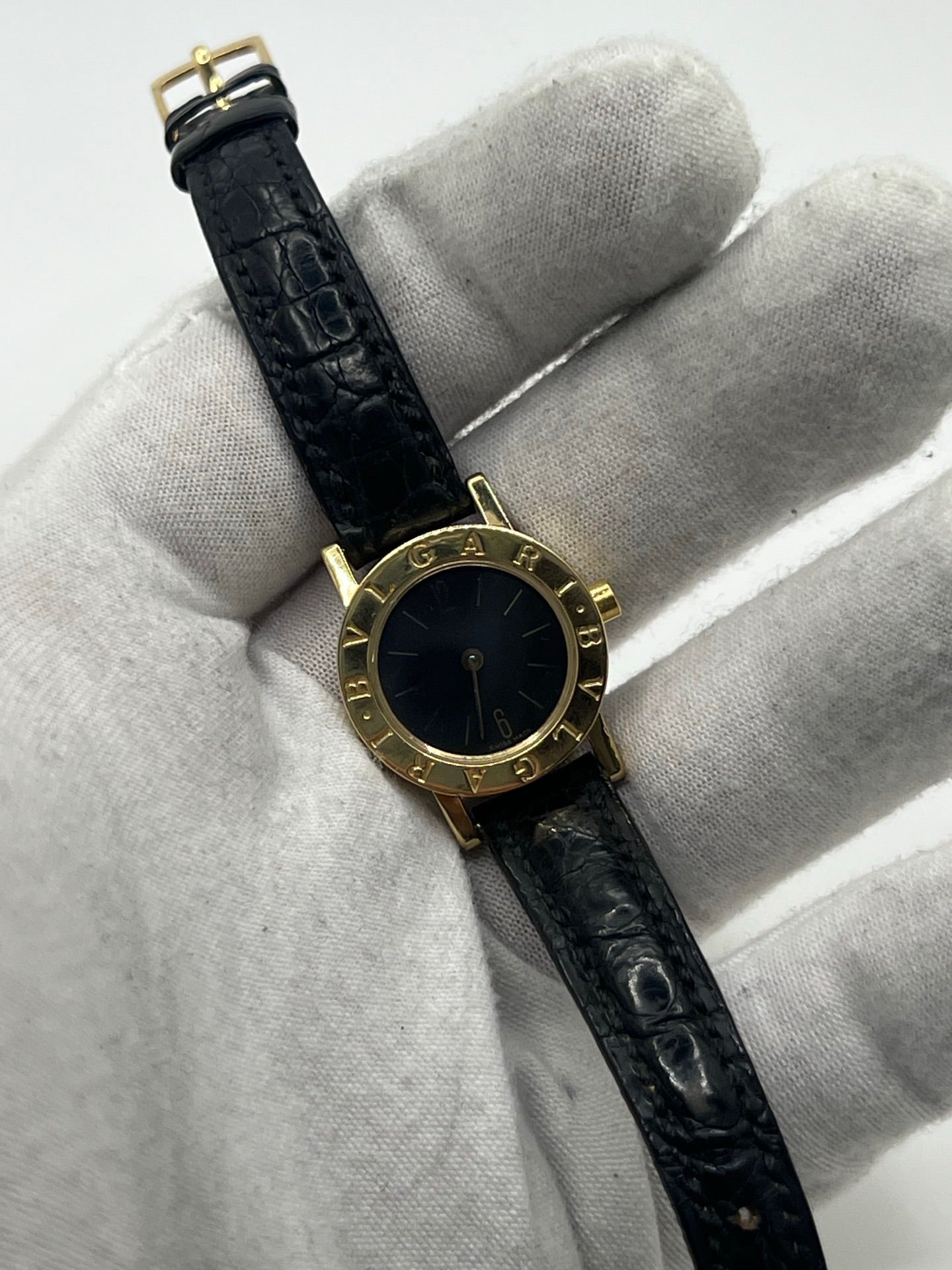 Montre femme Bulgari Bulgari Lady BB 23 GL en or jaune avec boîtier rond de 23 mm, cadran noir élégant et verre saphir. Cette montre de luxe à mouvement quartz est dotée d’un bracelet en cuir noir avec boucle ardillon en or jaune. Modèle emblématique au design intemporel, idéal pour un poignet féminin, alliant raffinement, précision et savoir-faire horloger italien. Parfaite comme montre habillée ou pièce de collection.