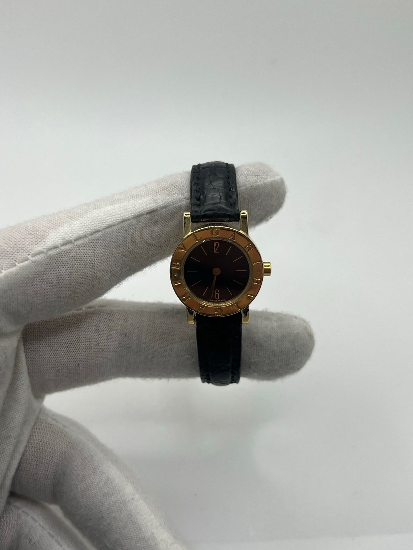 Montre femme Bulgari Bulgari Lady BB 23 GL en or jaune avec boîtier rond de 23 mm, cadran noir élégant et verre saphir. Cette montre de luxe à mouvement quartz est dotée d’un bracelet en cuir noir avec boucle ardillon en or jaune. Modèle emblématique au design intemporel, idéal pour un poignet féminin, alliant raffinement, précision et savoir-faire horloger italien. Parfaite comme montre habillée ou pièce de collection.