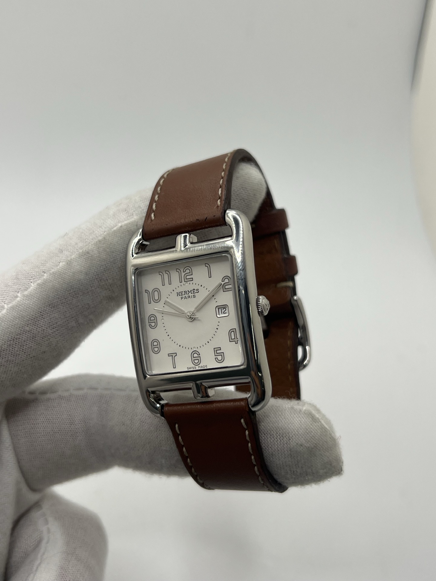 Montre Hermès Cape Cod Grand Modèle en acier inoxydable, boîtier rectangulaire iconique aux lignes élégantes et contemporaines, cadran argenté épuré avec chiffres arabes stylisés et aiguilles fines. Bracelet en cuir signature Hermès offrant confort et raffinement. Mouvement quartz précis. Montre de luxe intemporelle et sophistiquée, idéale pour un porté quotidien ou une tenue habillée, symbole du savoir-faire horloger et du style parisien.