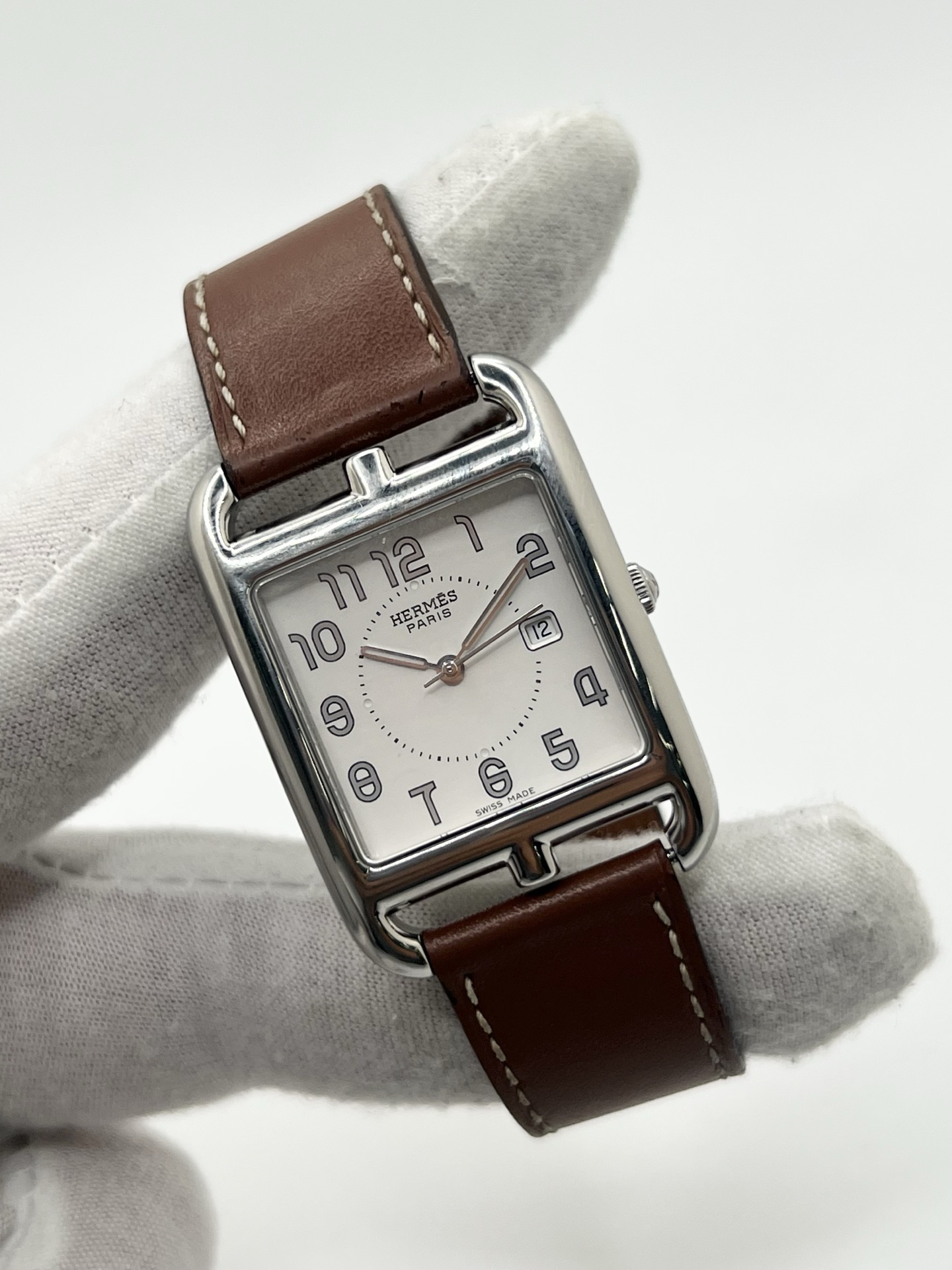 Montre Hermès Cape Cod Grand Modèle en acier inoxydable, boîtier rectangulaire iconique aux lignes élégantes et contemporaines, cadran argenté épuré avec chiffres arabes stylisés et aiguilles fines. Bracelet en cuir signature Hermès offrant confort et raffinement. Mouvement quartz précis. Montre de luxe intemporelle et sophistiquée, idéale pour un porté quotidien ou une tenue habillée, symbole du savoir-faire horloger et du style parisien.