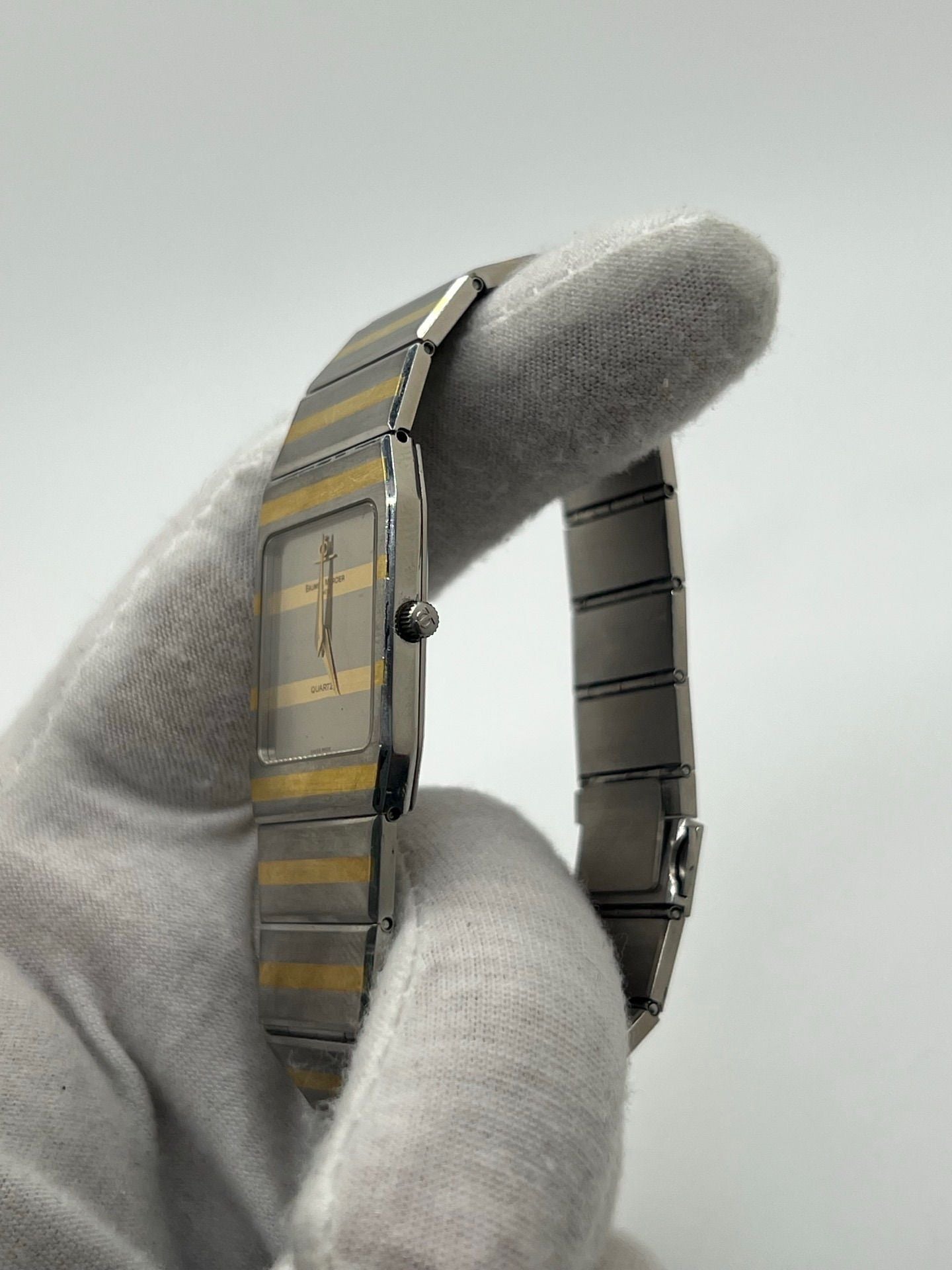 Montre Baume & Mercier Carlo Zebra 5739.038 pour homme/unisexe, mouvement quartz, boîtier acier 25x32 mm, cadran or, verre saphir et bracelet or/acier avec boucle pli. Étanche 10 ATM, d'occasion en bon état, disponible sans coffret ni papiers d'origine. Idéale pour les amateurs de montres de luxe élégantes et intemporelles.