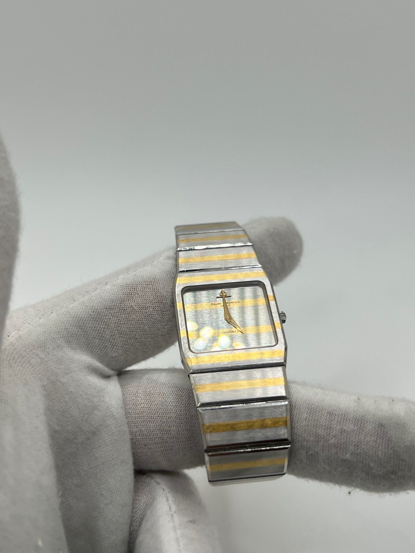 Montre Baume & Mercier Carlo Zebra 5739.038 pour homme/unisexe, mouvement quartz, boîtier acier 25x32 mm, cadran or, verre saphir et bracelet or/acier avec boucle pli. Étanche 10 ATM, d'occasion en bon état, disponible sans coffret ni papiers d'origine. Idéale pour les amateurs de montres de luxe élégantes et intemporelles.