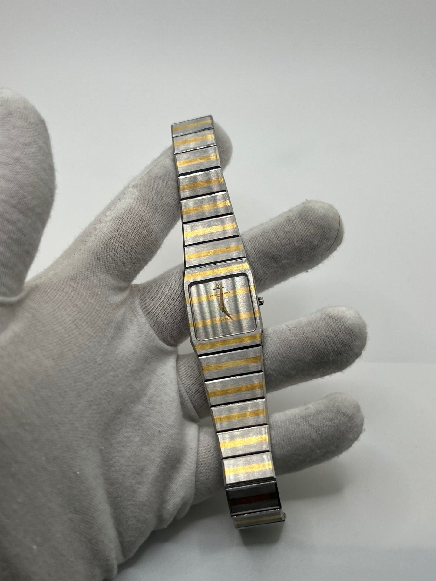 Montre Baume & Mercier Carlo Zebra 5739.038 pour homme/unisexe, mouvement quartz, boîtier acier 25x32 mm, cadran or, verre saphir et bracelet or/acier avec boucle pli. Étanche 10 ATM, d'occasion en bon état, disponible sans coffret ni papiers d'origine. Idéale pour les amateurs de montres de luxe élégantes et intemporelles.