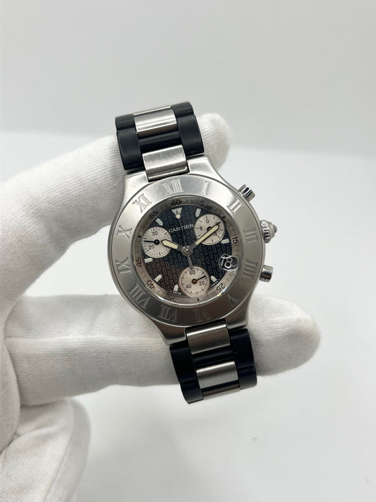 Montre Cartier 21 Chronoscaph 2424 à quartz, dotée d’un boîtier en acier de 38 mm et d’une épaisseur de 10 mm. Son cadran noir est protégé par un verre saphir et accompagné d’un bracelet en caoutchouc avec boucle déployante en acier. Étanche à 10 ATM, cette montre Cartier possède les fonctions chronographe et date. En très bon état, elle présente de légères traces d’usure et a été révisée en interne en septembre 2026.
