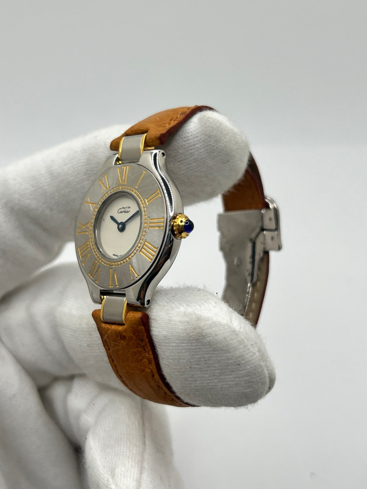 Montre Cartier 21 Must de Cartier 9011 pour femme, équipée d’un mouvement quartz et d’un boîtier en acier de 28 mm. Son cadran blanc offre une esthétique élégante et intemporelle. Cette montre Cartier est montée sur un bracelet brun en cuir avec boucle déployante à plis. En bon état, elle présente des traces d’usure visibles et perceptibles, notamment quelques rayures, éraflures et petites bosses. Révisée en interne en septembre 2026.
