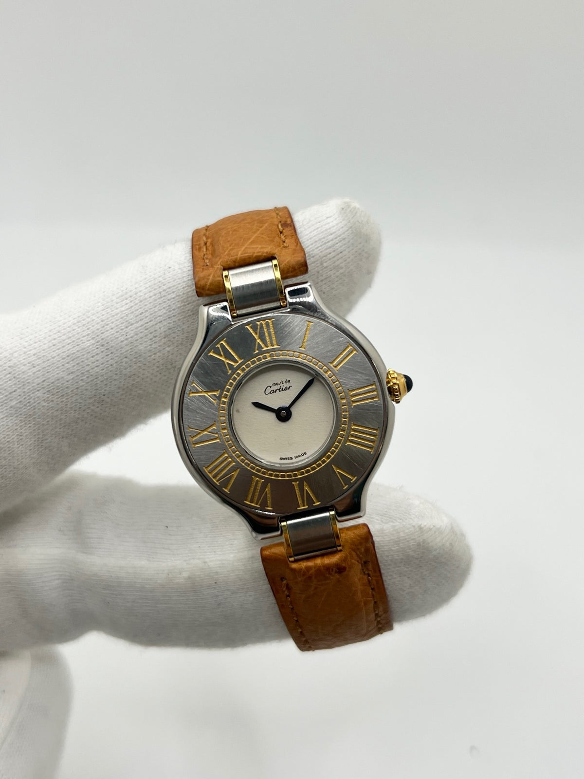 Montre Cartier 21 Must de Cartier 9011 pour femme, équipée d’un mouvement quartz et d’un boîtier en acier de 28 mm. Son cadran blanc offre une esthétique élégante et intemporelle. Cette montre Cartier est montée sur un bracelet brun en cuir avec boucle déployante à plis. En bon état, elle présente des traces d’usure visibles et perceptibles, notamment quelques rayures, éraflures et petites bosses. Révisée en interne en septembre 2026.
