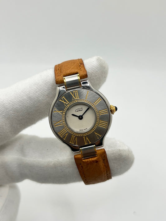 Montre Cartier 21 Must de Cartier 9011 pour femme, équipée d’un mouvement quartz et d’un boîtier en acier de 28 mm. Son cadran blanc offre une esthétique élégante et intemporelle. Cette montre Cartier est montée sur un bracelet brun en cuir avec boucle déployante à plis. En bon état, elle présente des traces d’usure visibles et perceptibles, notamment quelques rayures, éraflures et petites bosses. Révisée en interne en septembre 2026.
