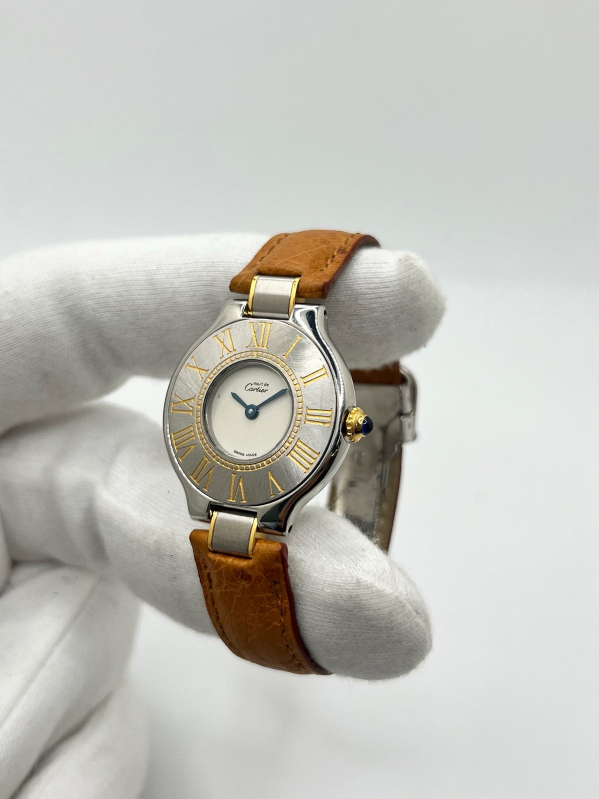 Montre Cartier 21 Must de Cartier 9011 pour femme, équipée d’un mouvement quartz et d’un boîtier en acier de 28 mm. Son cadran blanc offre une esthétique élégante et intemporelle. Cette montre Cartier est montée sur un bracelet brun en cuir avec boucle déployante à plis. En bon état, elle présente des traces d’usure visibles et perceptibles, notamment quelques rayures, éraflures et petites bosses. Révisée en interne en septembre 2026.
