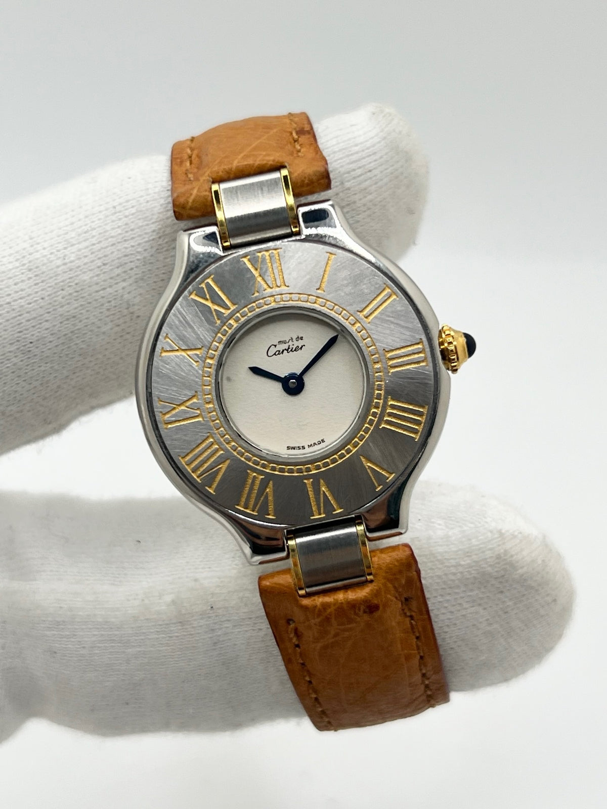 Montre Cartier 21 Must de Cartier 9011 pour femme, équipée d’un mouvement quartz et d’un boîtier en acier de 28 mm. Son cadran blanc offre une esthétique élégante et intemporelle. Cette montre Cartier est montée sur un bracelet brun en cuir avec boucle déployante à plis. En bon état, elle présente des traces d’usure visibles et perceptibles, notamment quelques rayures, éraflures et petites bosses. Révisée en interne en septembre 2026.
