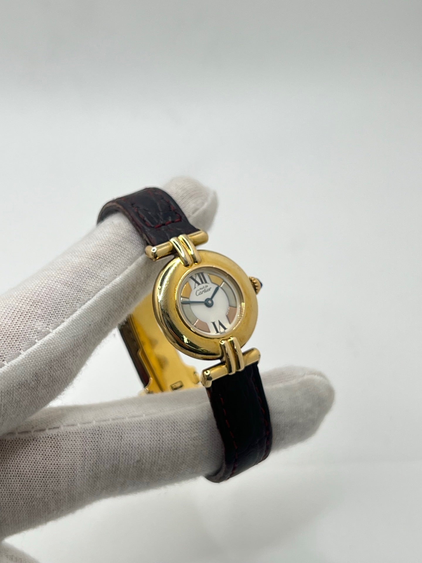 Montre femme Cartier Colisée réf. 590002 en argent avec mouvement quartz. Modèle vintage de 1995 au cadran blanc à chiffres romains et bracelet en cuir or. Verre saphir, boucle ardillon en argent. Élégance intemporelle signée Cartier, livrée avec coffret et papiers d’origine. Montre d’occasion en bon état, révisée en 2025.