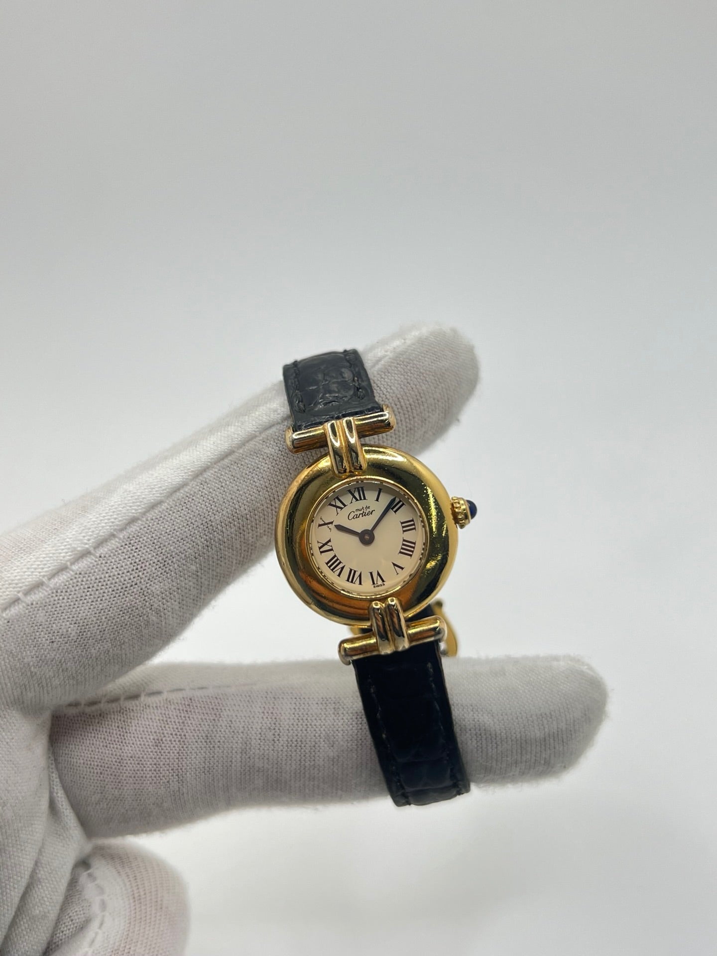 Montre Cartier Colisée Must Vermeil réf. 590002 pour femme, équipée d’un mouvement quartz précis. Boîtier en argent vermeil de 24 mm, cadran blanc à chiffres romains, verre saphir et bracelet en cuir noir avec boucle ardillon. Modèle d’occasion en bon état présentant quelques traces d’usure. Idéal pour les amateurs de montres élégantes et intemporelles.