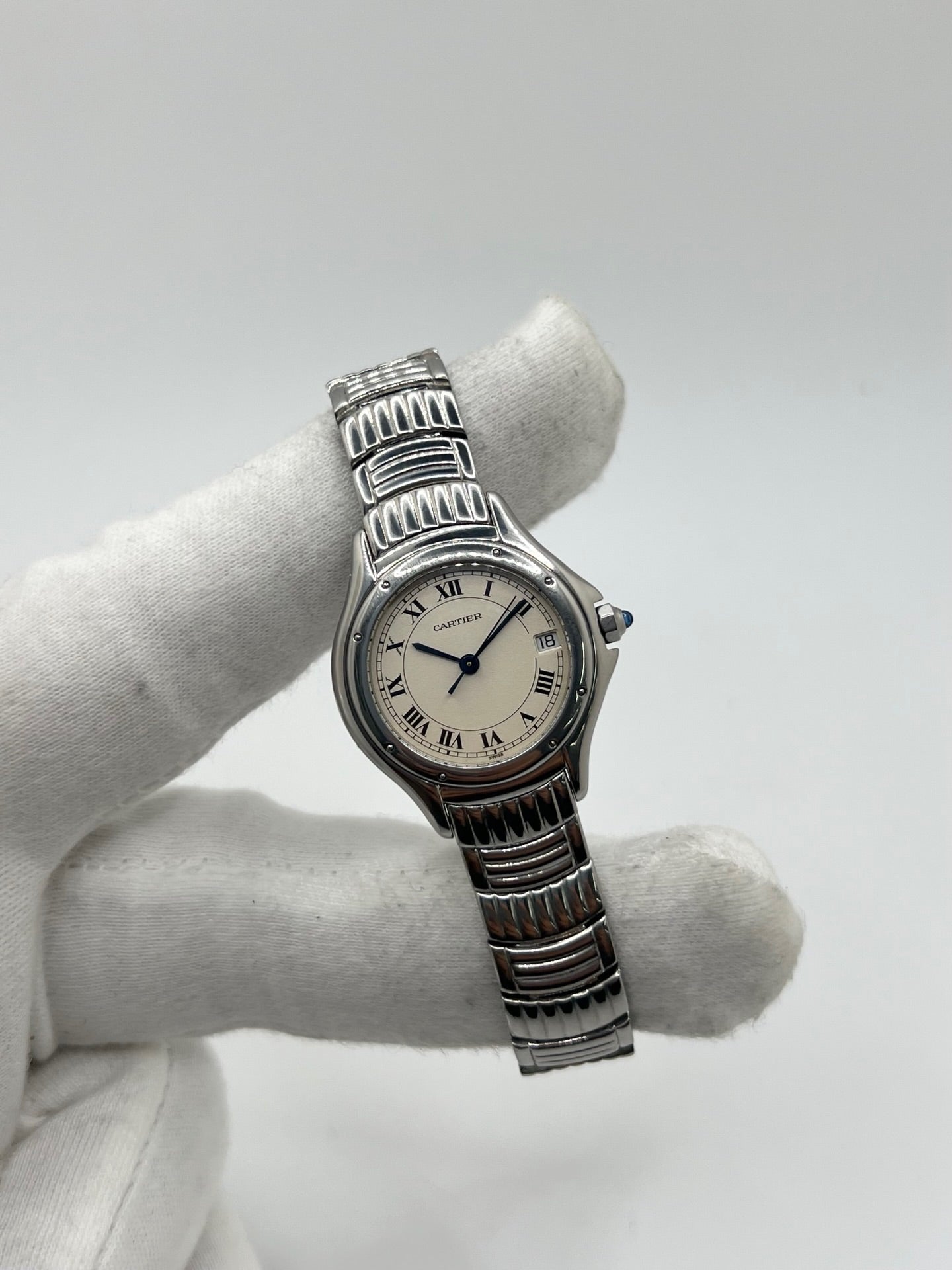 Montre Cartier Cougar référence 1215 1 en acier inoxydable avec boîtier de 26 mm et bracelet assorti. Ce modèle à mouvement quartz se distingue par son cadran blanc à chiffres romains, son verre saphir résistant aux rayures et son affichage de la date. Son design emblématique allie élégance et sobriété, caractéristique des créations horlogères de la maison Cartier. Montre d'occasion de 1995 en très bon état, révisée, avec coffret et papiers d'origine.
