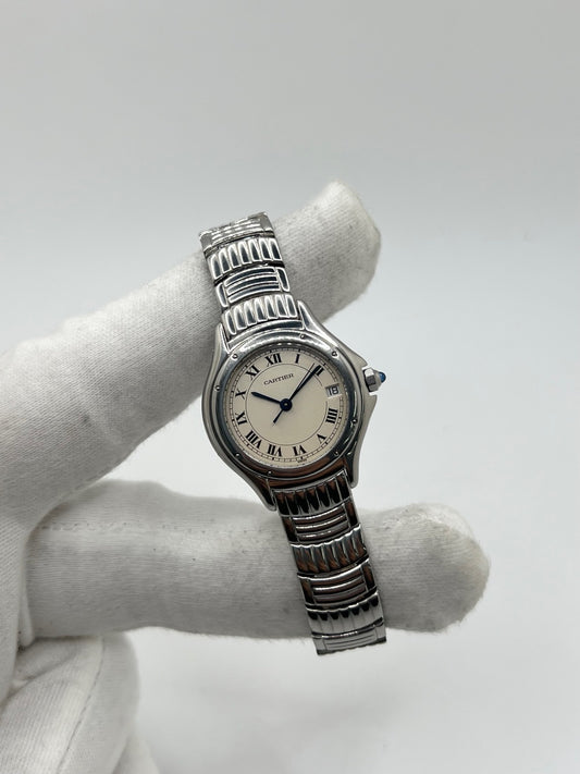 Montre Cartier Cougar référence 1215 1 en acier inoxydable avec boîtier de 26 mm et bracelet assorti. Ce modèle à mouvement quartz se distingue par son cadran blanc à chiffres romains, son verre saphir résistant aux rayures et son affichage de la date. Son design emblématique allie élégance et sobriété, caractéristique des créations horlogères de la maison Cartier. Montre d'occasion de 1995 en très bon état, révisée, avec coffret et papiers d'origine.

