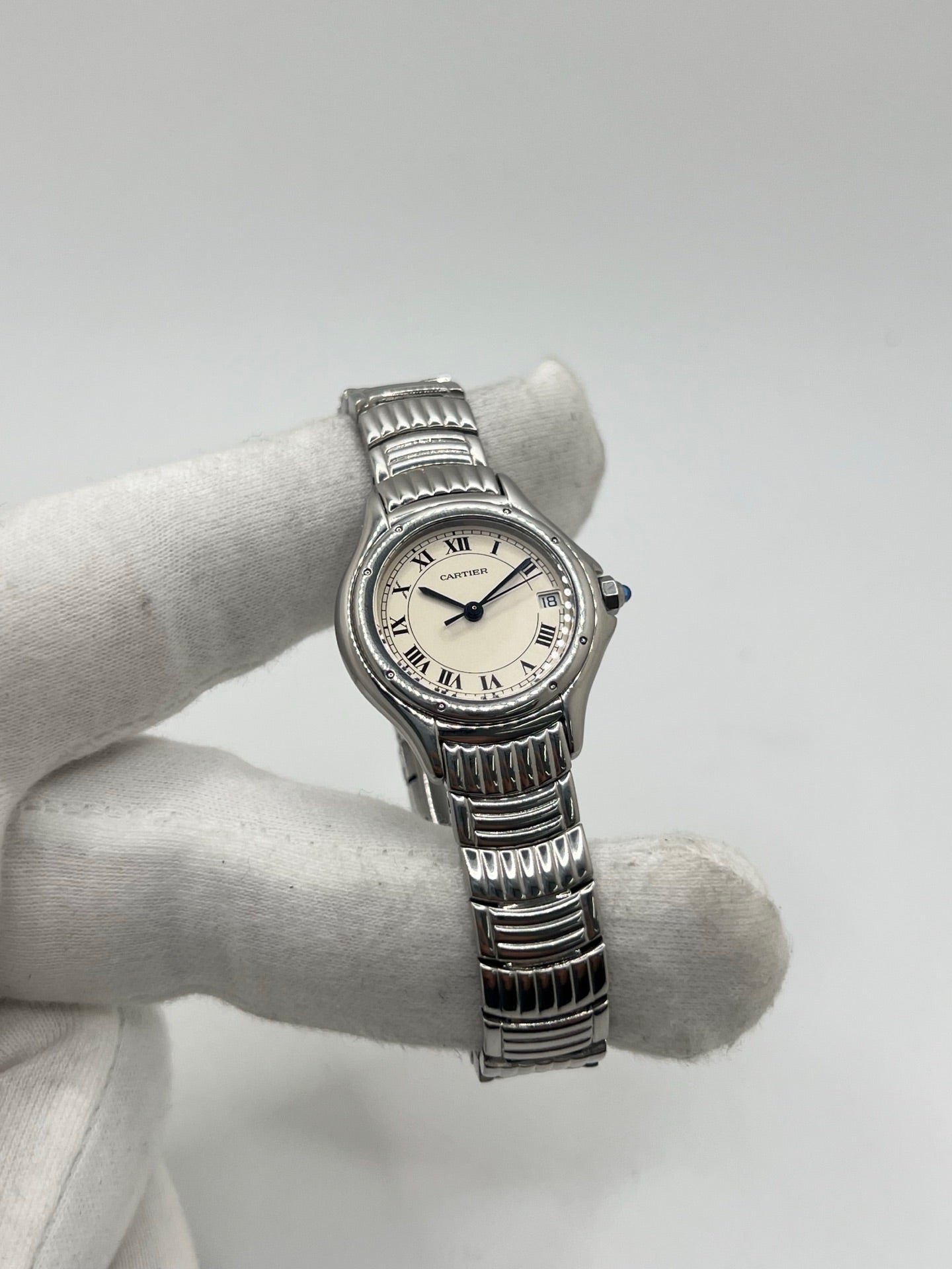 Montre Cartier Cougar référence 1215 1 en acier inoxydable avec boîtier de 26 mm et bracelet assorti. Ce modèle à mouvement quartz se distingue par son cadran blanc à chiffres romains, son verre saphir résistant aux rayures et son affichage de la date. Son design emblématique allie élégance et sobriété, caractéristique des créations horlogères de la maison Cartier. Montre d'occasion de 1995 en très bon état, révisée, avec coffret et papiers d'origine.
