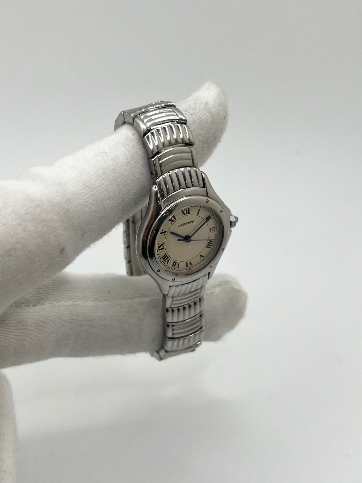 Montre Cartier Cougar référence 1215 1 en acier inoxydable avec boîtier de 26 mm et bracelet assorti. Ce modèle à mouvement quartz se distingue par son cadran blanc à chiffres romains, son verre saphir résistant aux rayures et son affichage de la date. Son design emblématique allie élégance et sobriété, caractéristique des créations horlogères de la maison Cartier. Montre d'occasion de 1995 en très bon état, révisée, avec coffret et papiers d'origine.
