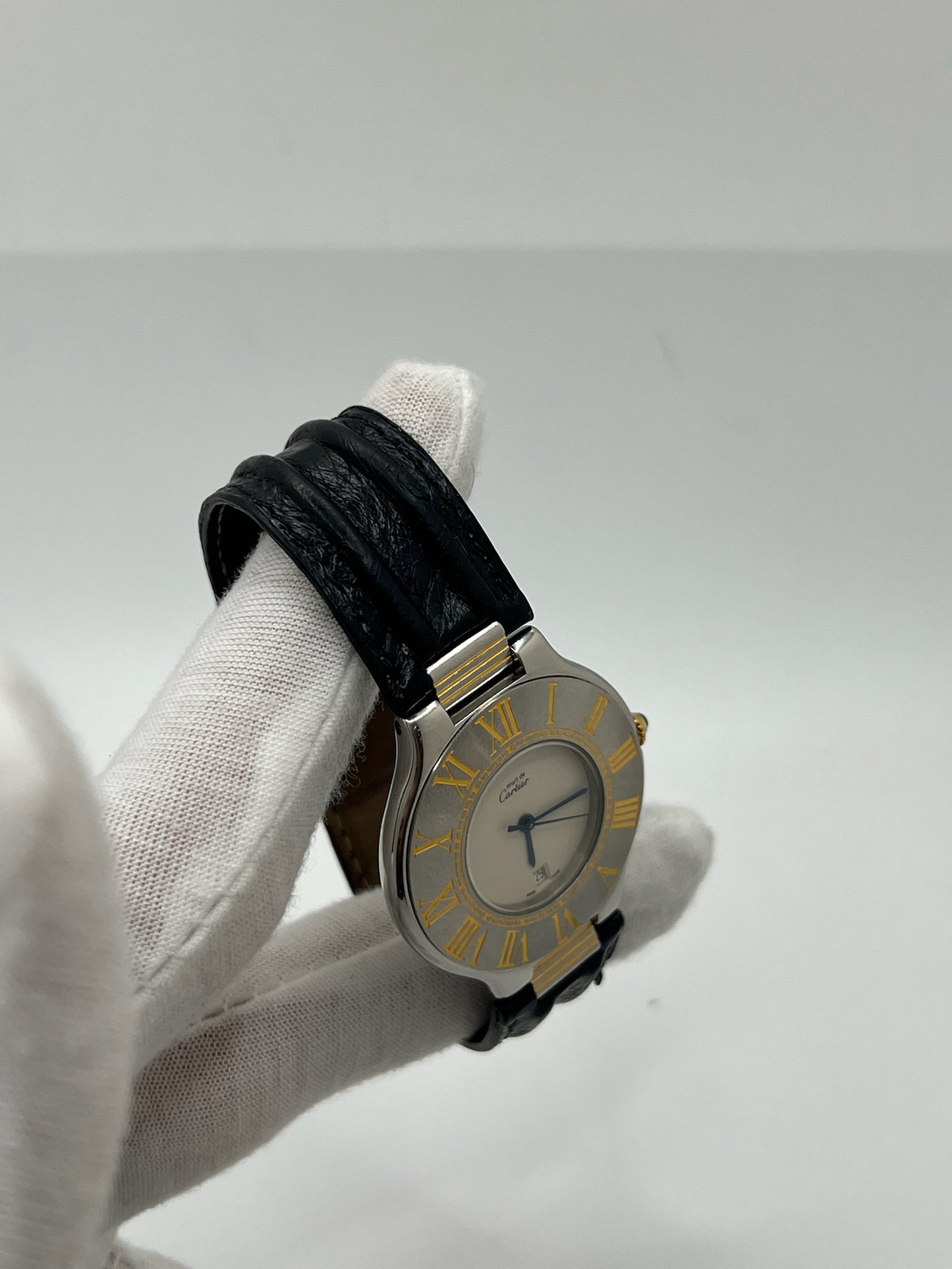 Montre Cartier 21 Must de Cartier avec boîtier 35 mm en or et acier, cadran blanc à chiffres romains, mouvement quartz. Modèle élégant et mixte, équipé d’une boucle déployante sur bracelet cuir noir. Montre de luxe vintage en très bon état, révisée, disponible sans boîte ni papiers d’origine. Idéale pour collectionneur ou amateur de montres emblématiques signées Cartier.