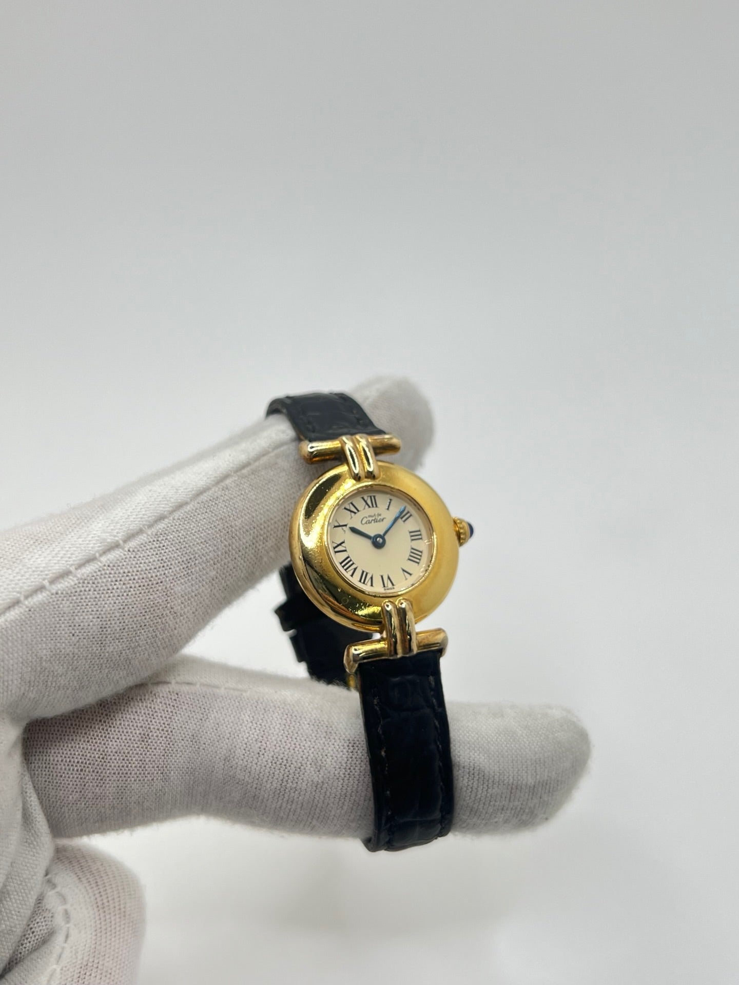 Montre Cartier Colisée Must Vermeil réf. 590002 pour femme, équipée d’un mouvement quartz précis. Boîtier en argent vermeil de 24 mm, cadran blanc à chiffres romains, verre saphir et bracelet en cuir noir avec boucle ardillon. Modèle d’occasion en bon état présentant quelques traces d’usure. Idéal pour les amateurs de montres élégantes et intemporelles.