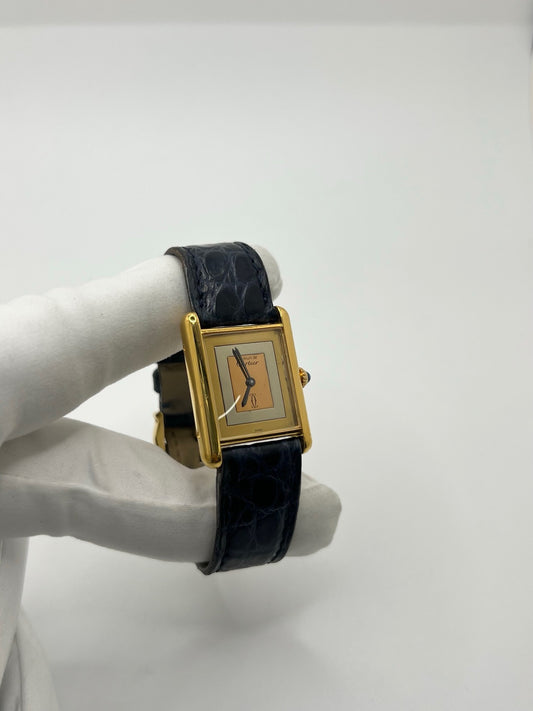 Montre Cartier Must de Cartier Tank Trinity en argent, à remontage manuel, avec boîtier de 23 x 30 mm et cadran jaune sans chiffres. Ce modèle emblématique est équipé d’un bracelet en cuir bleu avec boucle ardillon en acier, d’un verre minéral et d’une lunette en argent. Montre de luxe vintage homme ou unisexe, d’occasion en bon état, présentant des traces d’usure visibles. Révisée en interne, livrée avec coffret d’origine, idéale pour les collectionneurs de montres Cartier Tank Trinity.