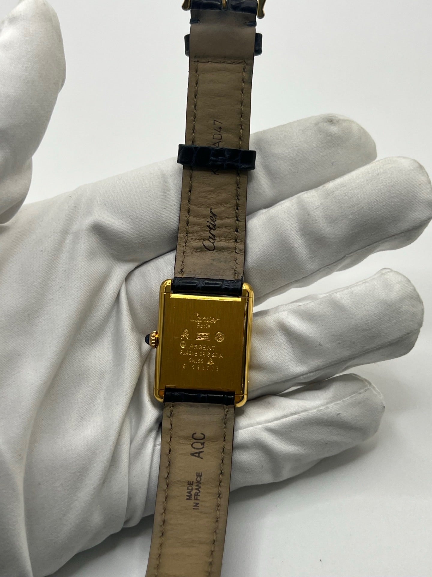Montre Cartier Must de Cartier Tank Trinity en argent, à remontage manuel, avec boîtier de 23 x 30 mm et cadran jaune sans chiffres. Ce modèle emblématique est équipé d’un bracelet en cuir bleu avec boucle ardillon en acier, d’un verre minéral et d’une lunette en argent. Montre de luxe vintage homme ou unisexe, d’occasion en bon état, présentant des traces d’usure visibles. Révisée en interne, livrée avec coffret d’origine, idéale pour les collectionneurs de montres Cartier Tank Trinity.