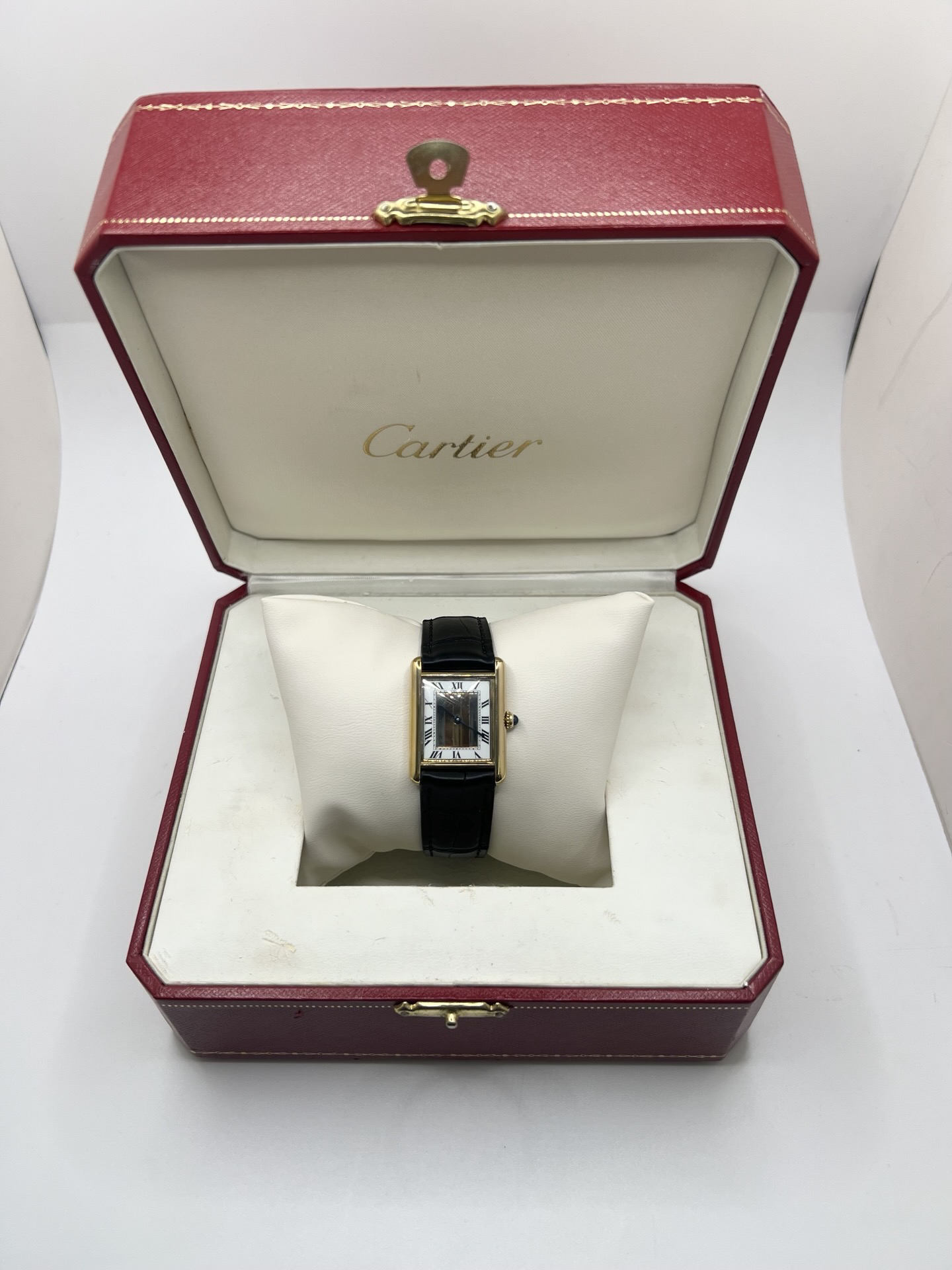 Montre Cartier Tank Must Trinity Grand Modèle vintage en vermeil, référence 590005, datant des années 1990. Boîtier rectangulaire de 23 x 30 mm en argent vermeil, cadran blanc à chiffres romains avec motif Trinity emblématique, verre saphir et mouvement quartz Cartier calibre 90. Bracelet en cuir avec boucle Cartier. Cette montre de luxe au design intemporel incarne l’élégance française et l’héritage horloger de Cartier, recherchée par les collectionneurs de montres vintage.