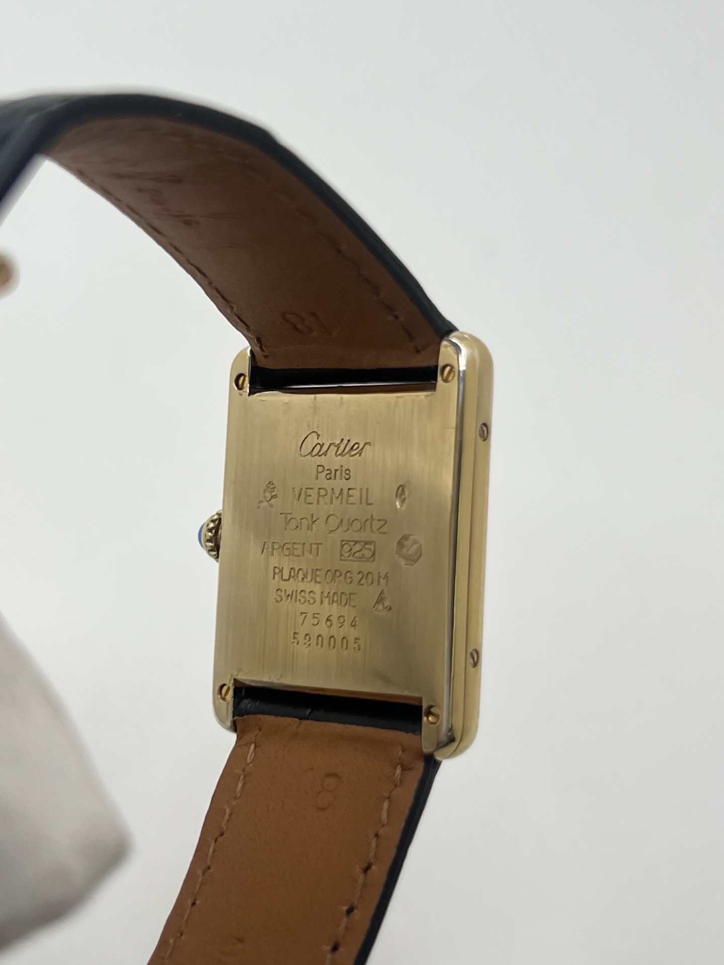Montre Cartier Tank Must Trinity Grand Modèle vintage en vermeil, référence 590005, datant des années 1990. Boîtier rectangulaire de 23 x 30 mm en argent vermeil, cadran blanc à chiffres romains avec motif Trinity emblématique, verre saphir et mouvement quartz Cartier calibre 90. Bracelet en cuir avec boucle Cartier. Cette montre de luxe au design intemporel incarne l’élégance française et l’héritage horloger de Cartier, recherchée par les collectionneurs de montres vintage.