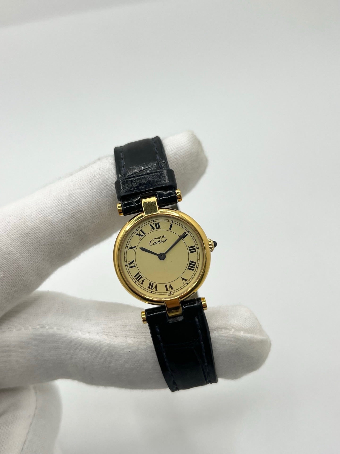 Montre Cartier Must Vendôme en vermeil, boîtier en argent plaqué or au diamètre de 30 mm, accompagnée d’un cadran blanc à chiffres romains signature. Équipée d’un mouvement quartz précis et d’un bracelet en cuir noir avec boucle en acier. Modèle élégant et intemporel, idéal pour un poignet féminin. Montre d’occasion en très bon état, présentant de légères micro-rayures, révisée en interne, livrée avec son coffret d’origine.