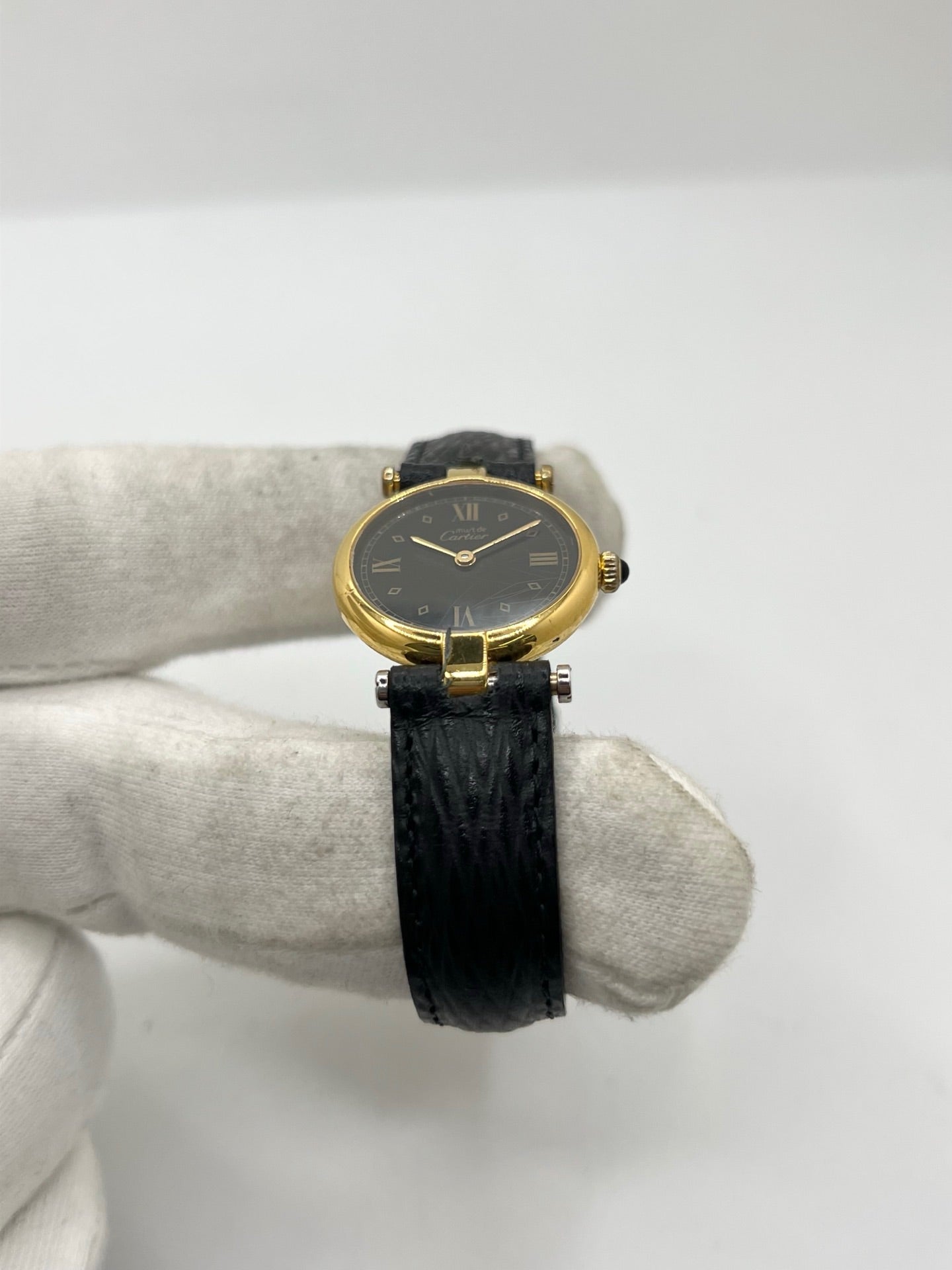 Cartier Must Vendôme référence 590004 en argent avec boîtier de 24 mm, cadran noir à chiffres romains et mouvement à quartz. Cette montre femme est équipée d'un bracelet en cuir, d'une boucle ardillon en acier et d'un verre saphir. Modèle d'occasion en très bon état, révisé en interne en 2026. Une montre Cartier vintage au design élégant, idéale pour les amateurs d'horlogerie de luxe et de pièces intemporelles.
