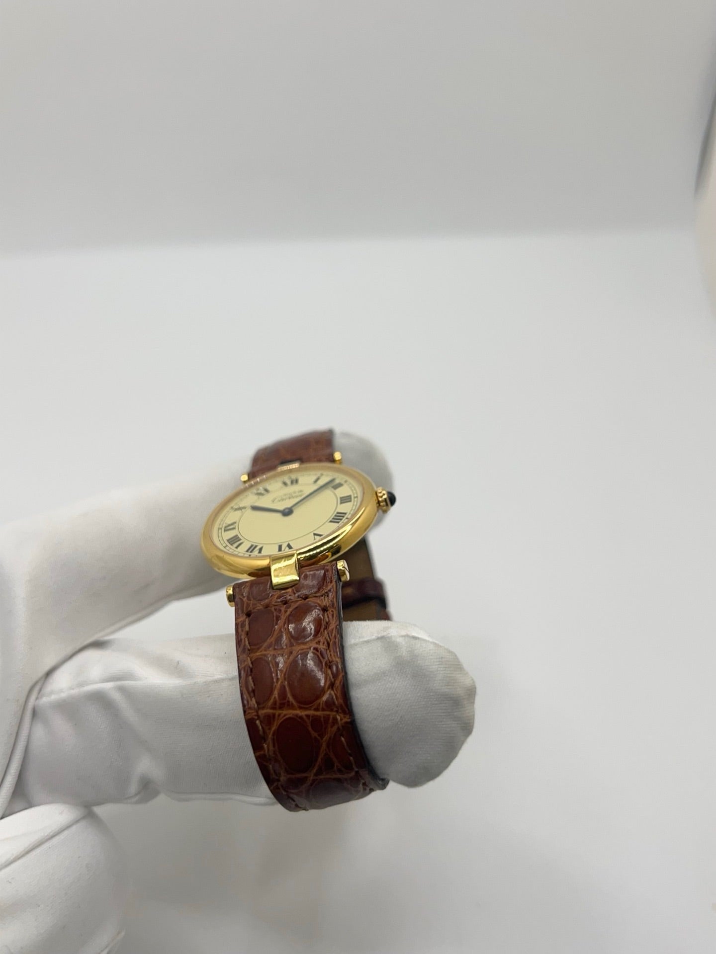 Montre Cartier Must Vendôme réf. 590003 en argent, cadran doré à chiffres romains, boîtier 30 mm avec verre saphir. Mouvement quartz fiable, bracelet cuir noir avec boucle ardillon. Modèle vintage de 1990 en très bon état, avec légères micro-rayures peu visibles. Livrée avec coffret et papiers d’origine, révisée en 2026.