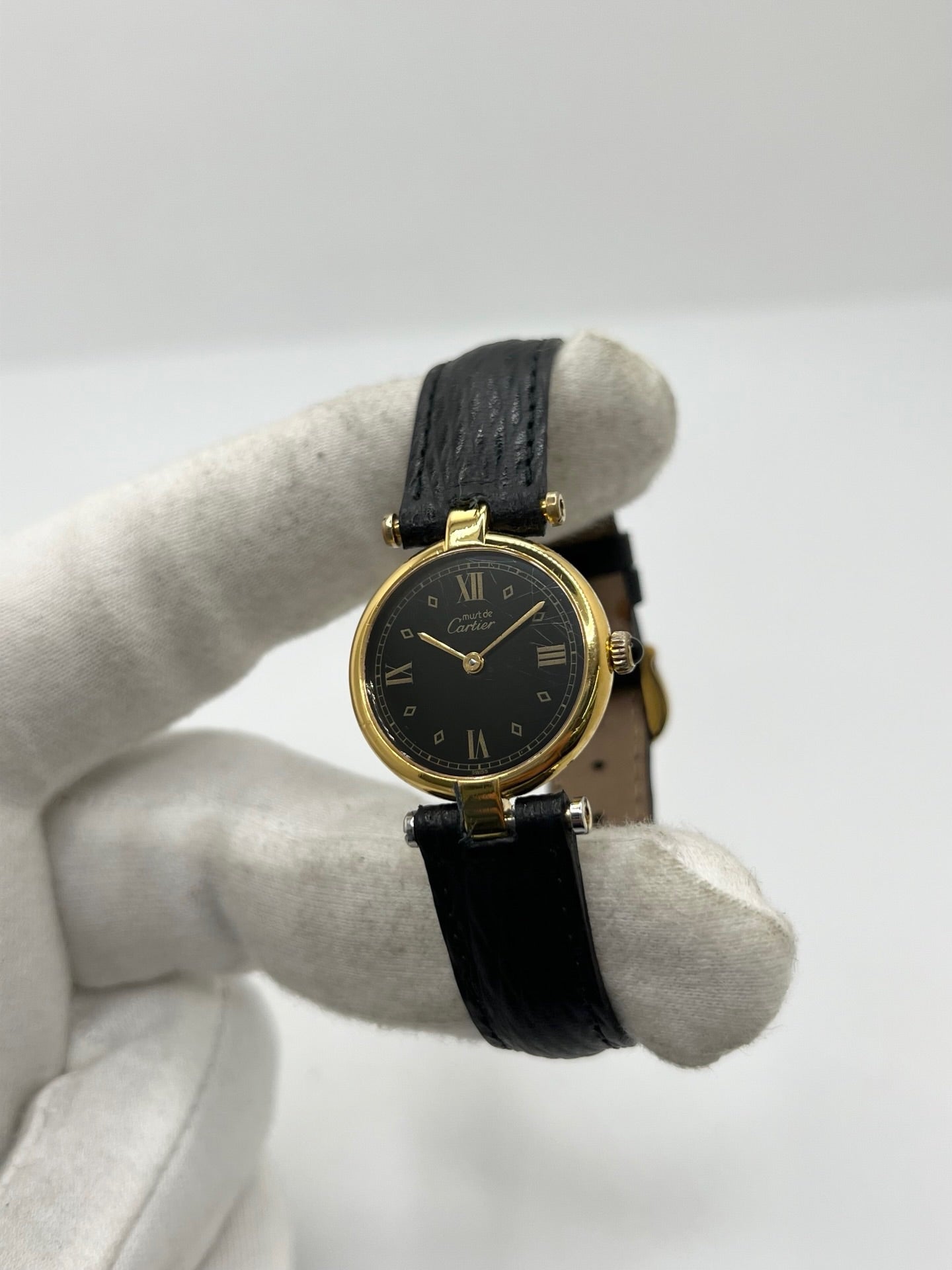 Cartier Must Vendôme référence 590004 en argent avec boîtier de 24 mm, cadran noir à chiffres romains et mouvement à quartz. Cette montre femme est équipée d'un bracelet en cuir, d'une boucle ardillon en acier et d'un verre saphir. Modèle d'occasion en très bon état, révisé en interne en 2026. Une montre Cartier vintage au design élégant, idéale pour les amateurs d'horlogerie de luxe et de pièces intemporelles.
