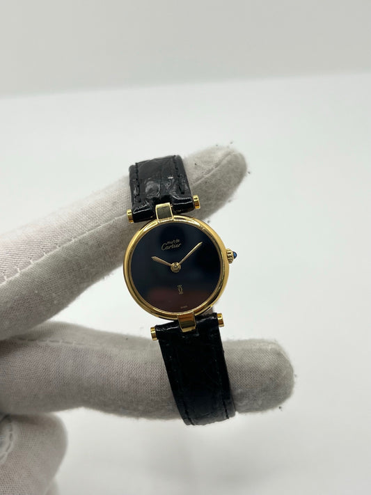 Montre Cartier Must Vendome pour femme, équipée d’un mouvement quartz et d’un boîtier en argent de 24 mm. Ce modèle d’occasion en très bon état dispose d’un cadran noir sans chiffres, d’un verre saphir et d’un bracelet en cuir avec boucle ardillon en acier. Élégante et raffinée, la Cartier Must Vendome séduit par son design classique et intemporel, idéale pour les passionnées de montres de luxe au style discret et sophistiqué.