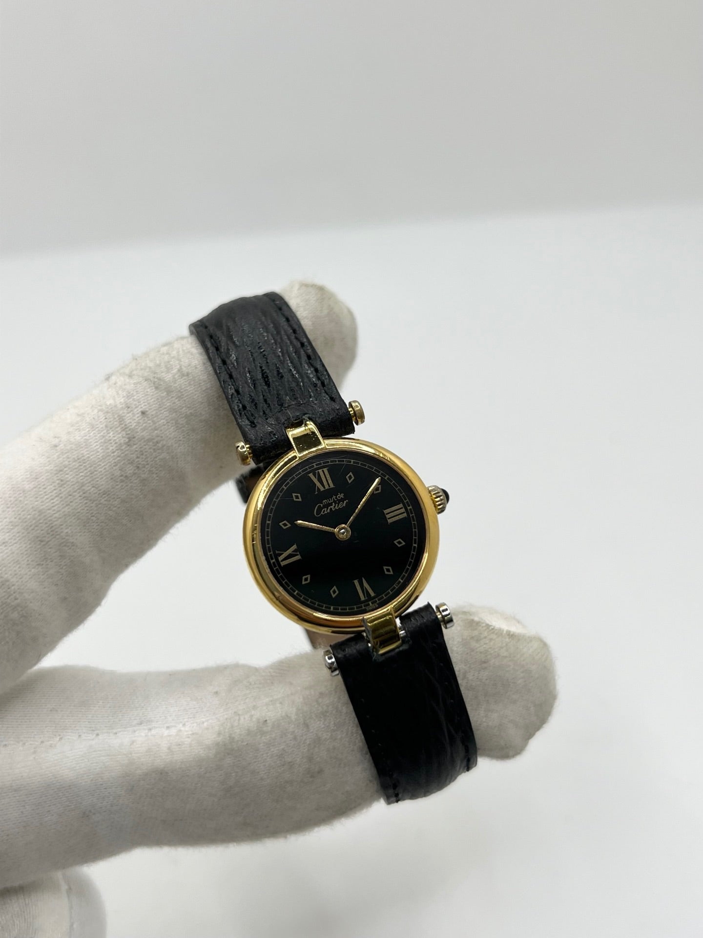 Cartier Must Vendôme référence 590004 en argent avec boîtier de 24 mm, cadran noir à chiffres romains et mouvement à quartz. Cette montre femme est équipée d'un bracelet en cuir, d'une boucle ardillon en acier et d'un verre saphir. Modèle d'occasion en très bon état, révisé en interne en 2026. Une montre Cartier vintage au design élégant, idéale pour les amateurs d'horlogerie de luxe et de pièces intemporelles.
