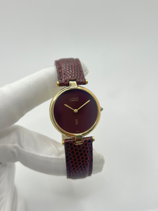 Montre Cartier Must Vendôme Vermeil 30 mm avec cadran bordeaux “burgundy”. Ce modèle vintage emblématique présente un boîtier rond en vermeil (argent plaqué or), un cadran laqué rouge profond signature de la collection Must, des aiguilles dorées élégantes et un design classique intemporel. Montre de luxe suisse recherchée par les collectionneurs, idéale pour les amateurs d’horlogerie vintage et de pièces iconiques au style raffiné.
