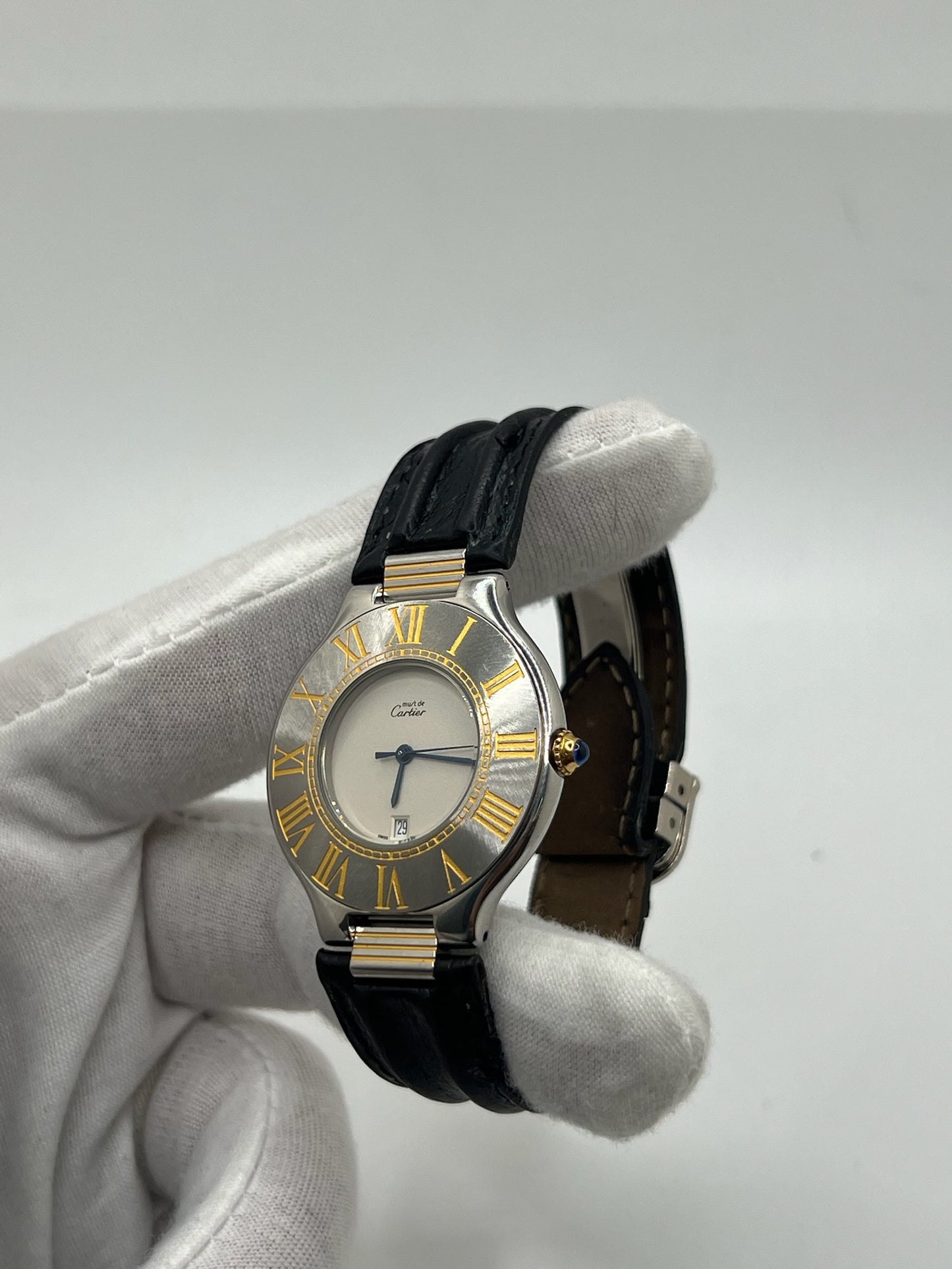 Montre Cartier 21 Must de Cartier avec boîtier 35 mm en or et acier, cadran blanc à chiffres romains, mouvement quartz. Modèle élégant et mixte, équipé d’une boucle déployante sur bracelet cuir noir. Montre de luxe vintage en très bon état, révisée, disponible sans boîte ni papiers d’origine. Idéale pour collectionneur ou amateur de montres emblématiques signées Cartier.