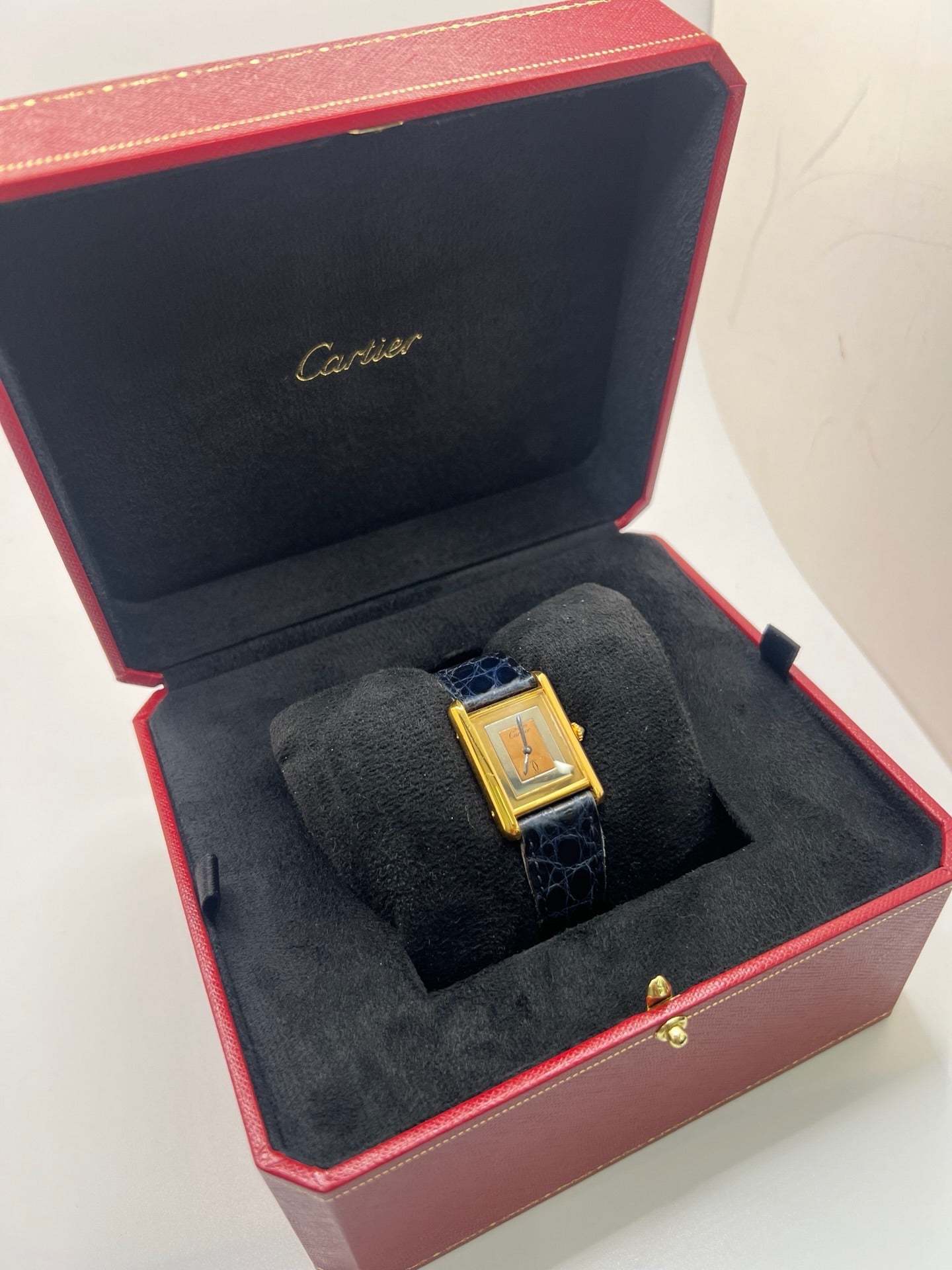 Montre Cartier Must de Cartier Tank Trinity en argent, à remontage manuel, avec boîtier de 23 x 30 mm et cadran jaune sans chiffres. Ce modèle emblématique est équipé d’un bracelet en cuir bleu avec boucle ardillon en acier, d’un verre minéral et d’une lunette en argent. Montre de luxe vintage homme ou unisexe, d’occasion en bon état, présentant des traces d’usure visibles. Révisée en interne, livrée avec coffret d’origine, idéale pour les collectionneurs de montres Cartier Tank Trinity.