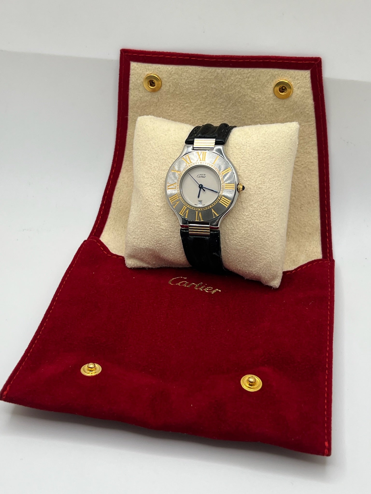 Montre Cartier 21 Must de Cartier avec boîtier 35 mm en or et acier, cadran blanc à chiffres romains, mouvement quartz. Modèle élégant et mixte, équipé d’une boucle déployante sur bracelet cuir noir. Montre de luxe vintage en très bon état, révisée, disponible sans boîte ni papiers d’origine. Idéale pour collectionneur ou amateur de montres emblématiques signées Cartier.