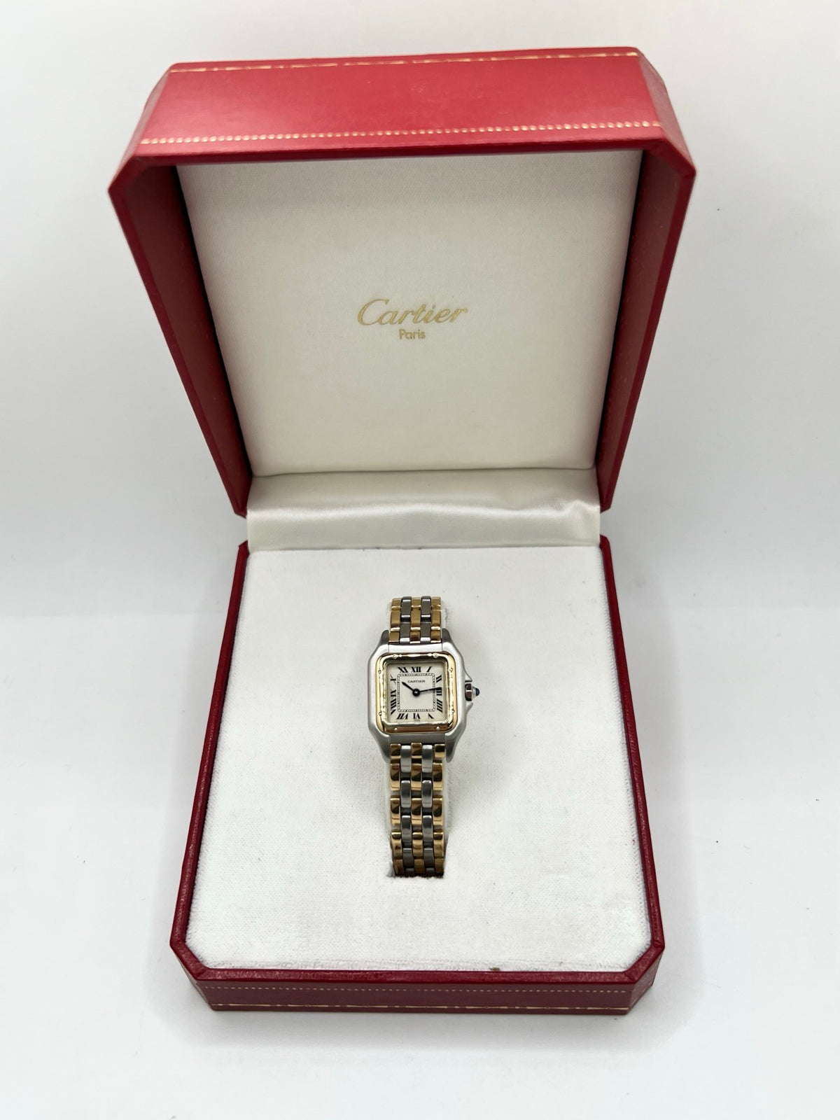 Montre Cartier Panthère 1057917 pour femme, modèle emblématique de la maison Cartier datant de 1989. Cette montre de luxe vintage associe élégamment l’or et l’acier, avec un cadran blanc raffiné, un verre saphir et un mouvement à quartz. La Cartier Panthère référence 1057917 est proposée d’occasion en très bon état, avec son coffret et ses papiers d’origine. Révisée en interne le 19 octobre 2026, cette montre Cartier Panthère en or et acier allie élégance intemporelle et savoir-faire horloger.