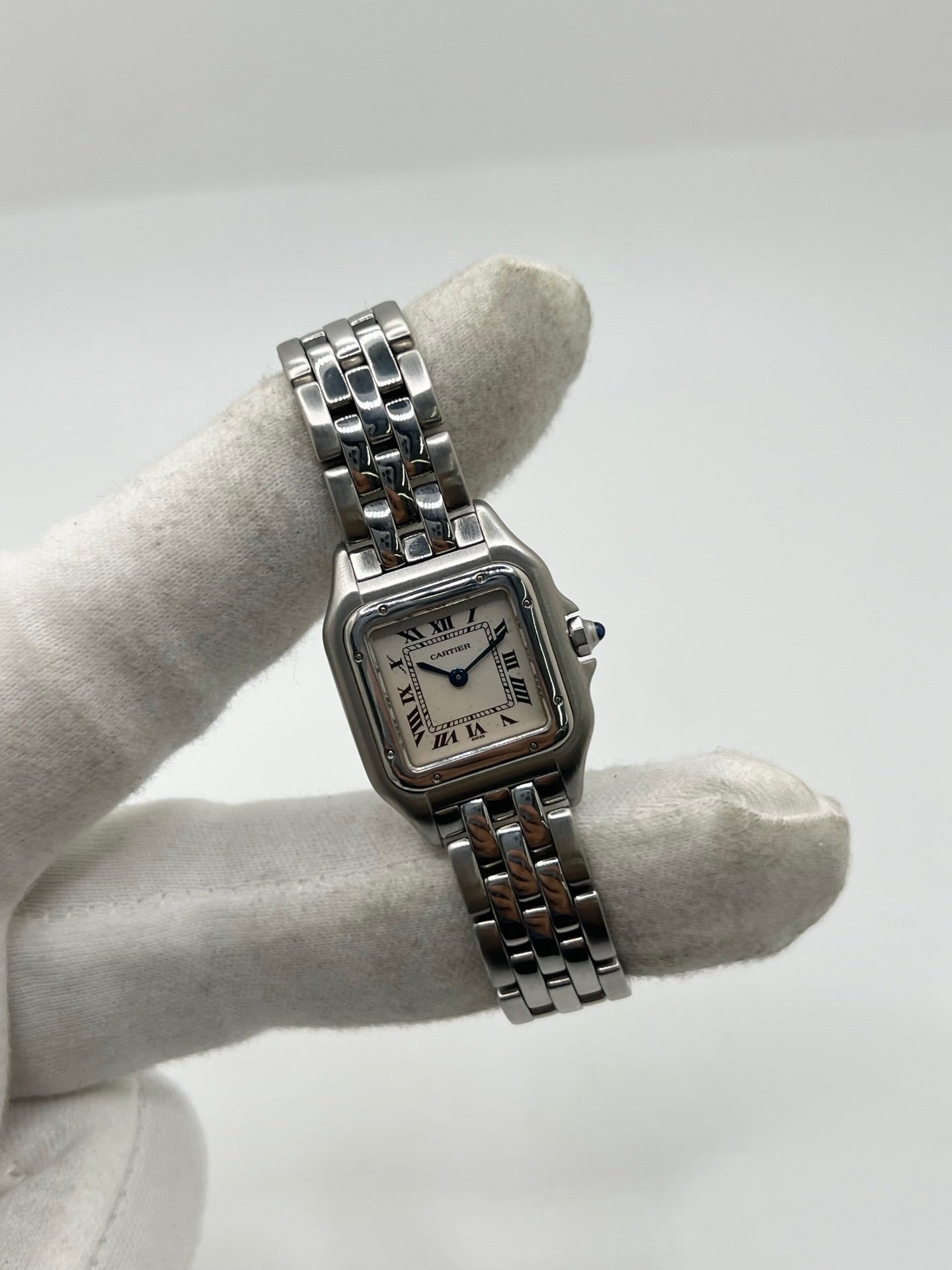 Cartier Panthère référence 1320 en acier avec boîtier de 22 mm, cadran blanc à chiffres romains et mouvement à quartz. Cette montre femme est équipée d'un bracelet en acier avec boucle déployante double pli et d'un verre saphir. Modèle d'occasion en très bon état, révisé par le fabricant en 2026, livré avec son coffret et ses papiers d'origine.