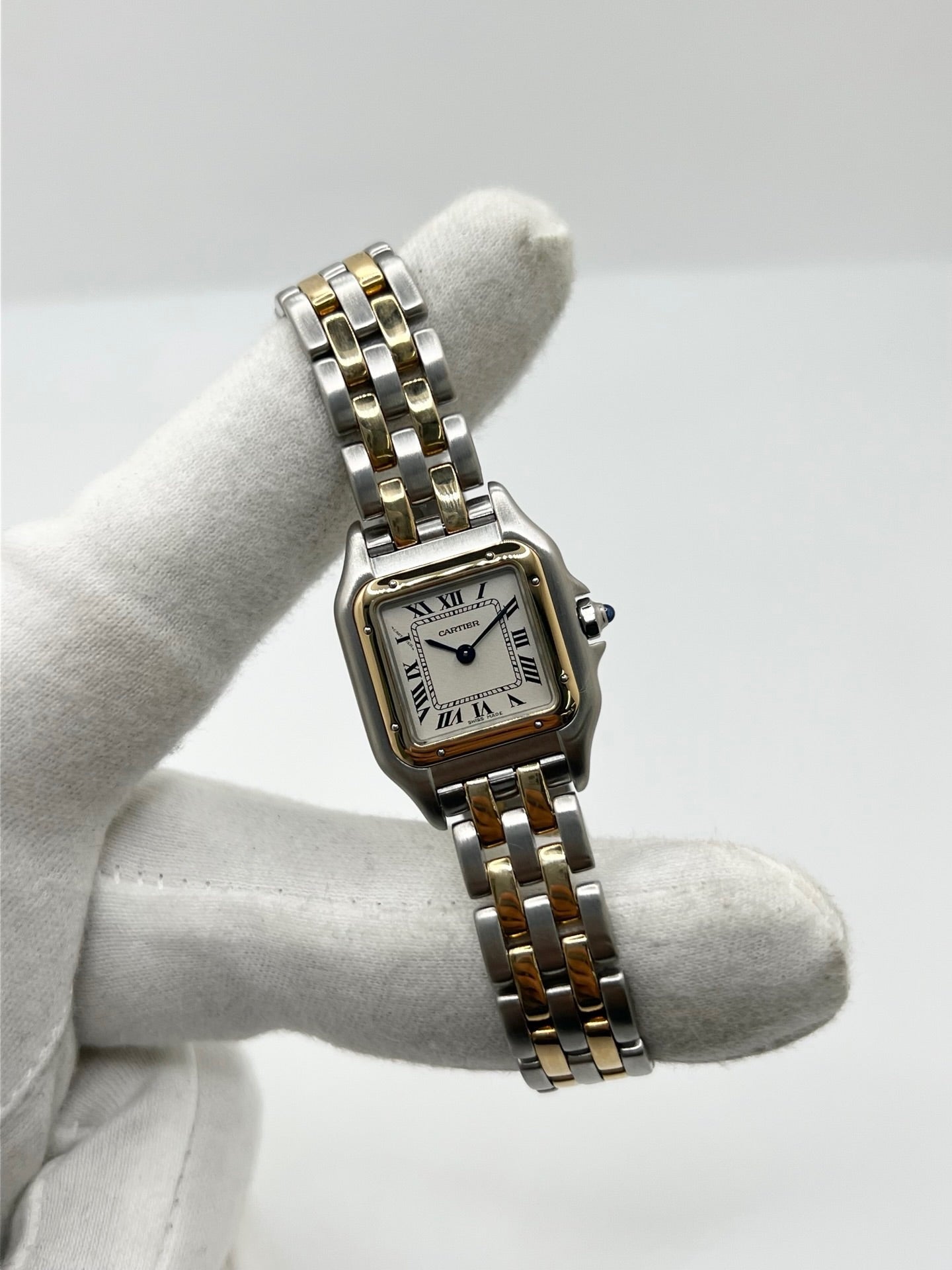 Montre Cartier Panthère référence 66921 pour femme en or jaune et acier, fabriquée en 1985 et équipée d'un mouvement quartz Swiss movement. Son boîtier rectangulaire de 22 x 30 mm est sublimé par une lunette en or jaune, un cadran blanc à chiffres romains et un verre saphir. Cette montre Cartier Panthère bicolore dispose d'un bracelet en or et acier avec boucle déployante. Vendue avec son coffret et ses papiers d'origine, elle est en très bon état et révisée en interne.