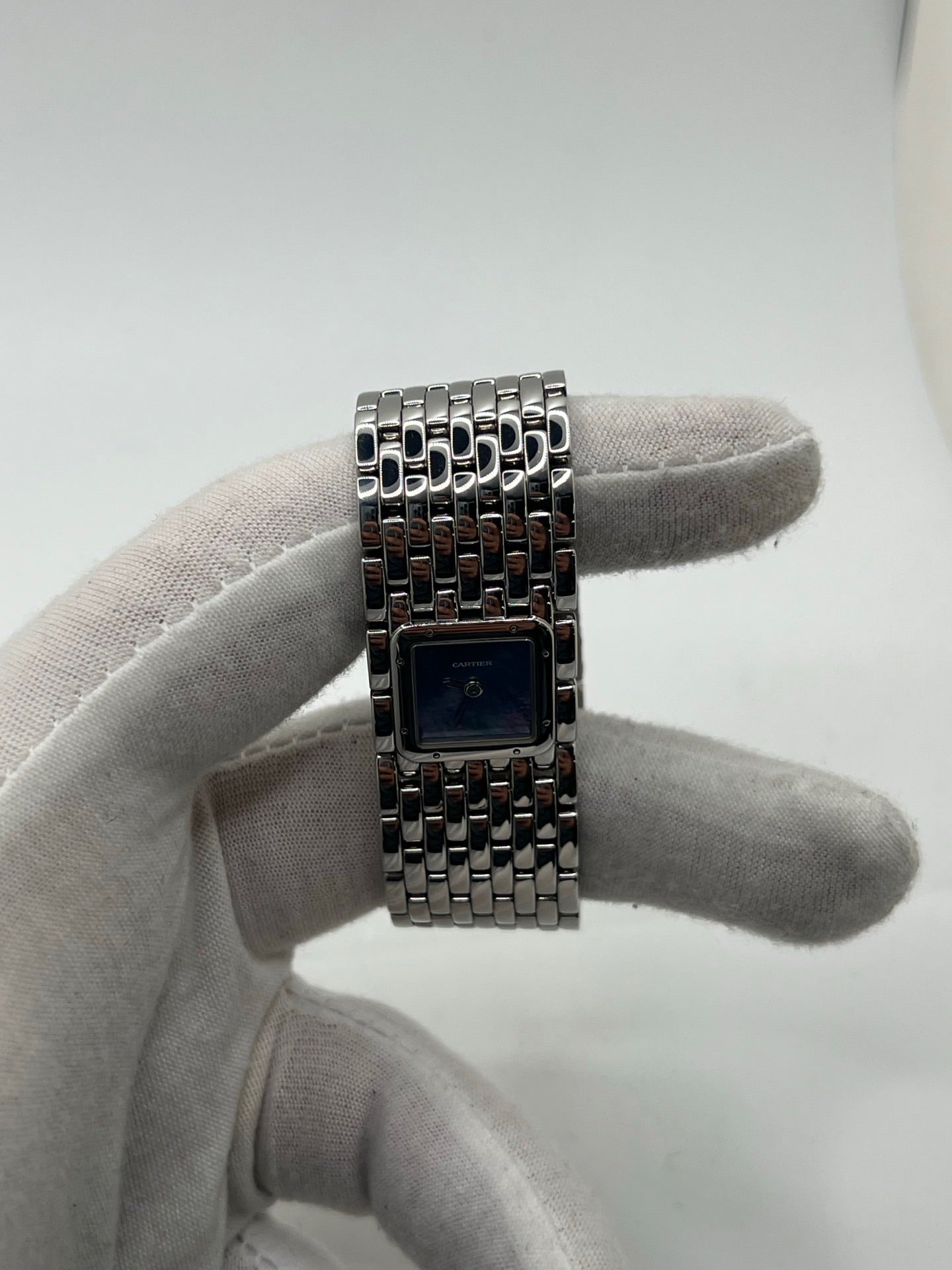 Montre femme de la maison Cartier, modèle Panthère Ruban réf. 2420, en acier avec boîtier de 21 mm et lunette assortie, verre saphir, cadran en nacre aux chiffres romains, mouvement quartz précis, bracelet acier avec boucle double plis. Étanchéité 3 ATM. D’occasion en très bon état, livrée avec coffret d’origine, élégante et intemporelle pour un style raffiné au quotidien ou en occasion spéciale.