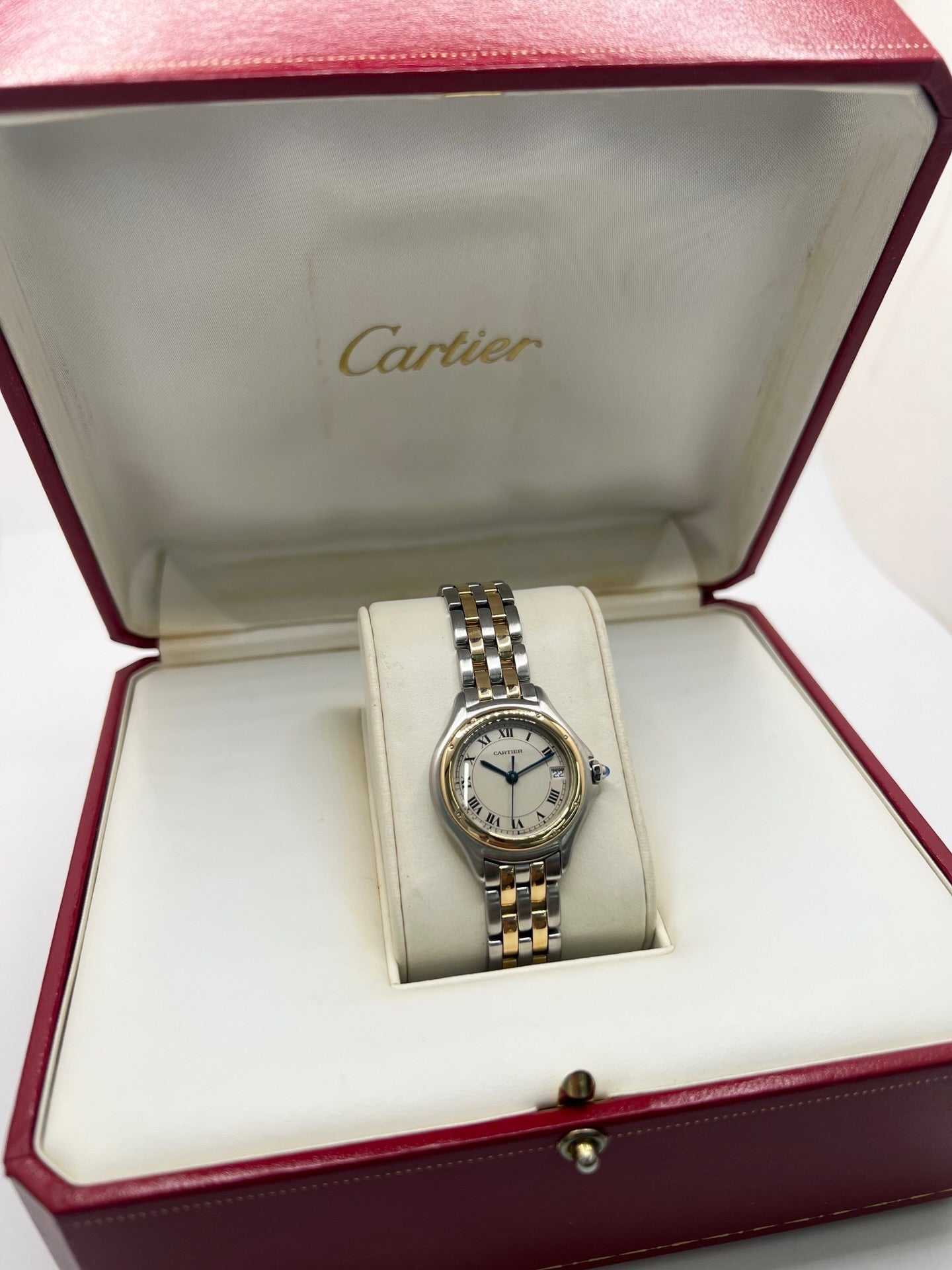 Montre Cartier Panthère référence 119000R pour femme en or jaune et acier, équipée d'un mouvement à quartz. Son boîtier de 26 mm est sublimé par une lunette en or jaune, un cadran blanc à chiffres romains et un verre saphir résistant aux rayures. Son bracelet bicolore en or et acier avec boucle déployante assure un porté confortable. Cette montre d'occasion est en très bon état, révisée en interne et livrée avec son coffret d'origine.