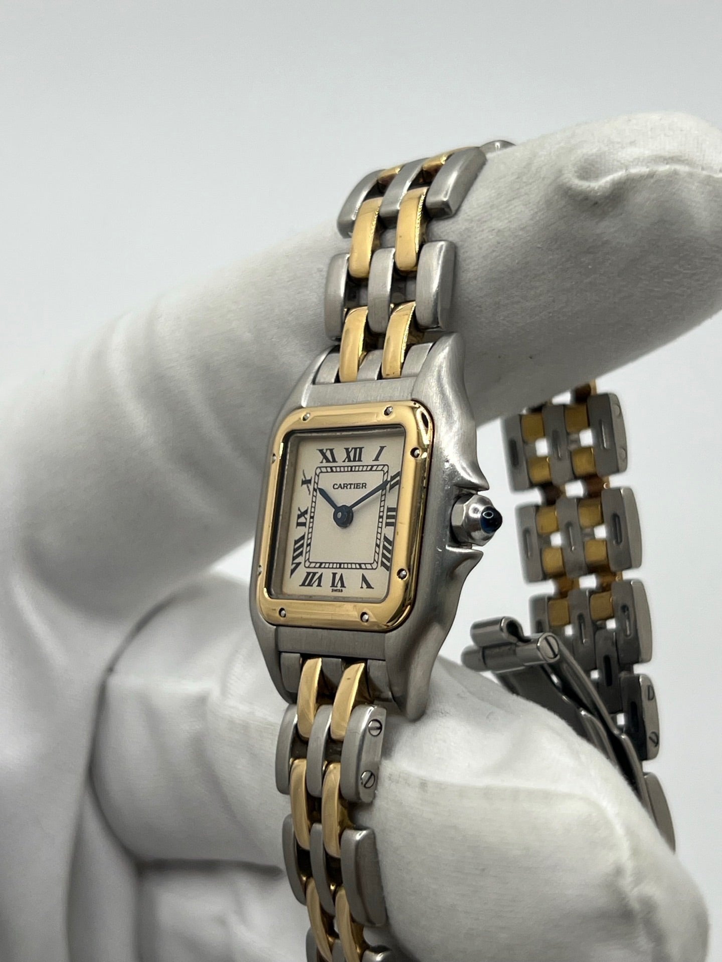 Montre Cartier Panthère 166921 pour femme en or et acier, équipée d’un mouvement quartz suisse. Ce modèle iconique présente un boîtier de 22 x 21 mm, une lunette en or jaune, un cadran blanc à chiffres romains et un verre saphir. Son bracelet en or et acier avec boucle double plis complète son élégance intemporelle. Montre de luxe d’occasion en très bon état, révisée, avec coffret d’origine, idéale pour les amateurs de montres Cartier Panthère femme.