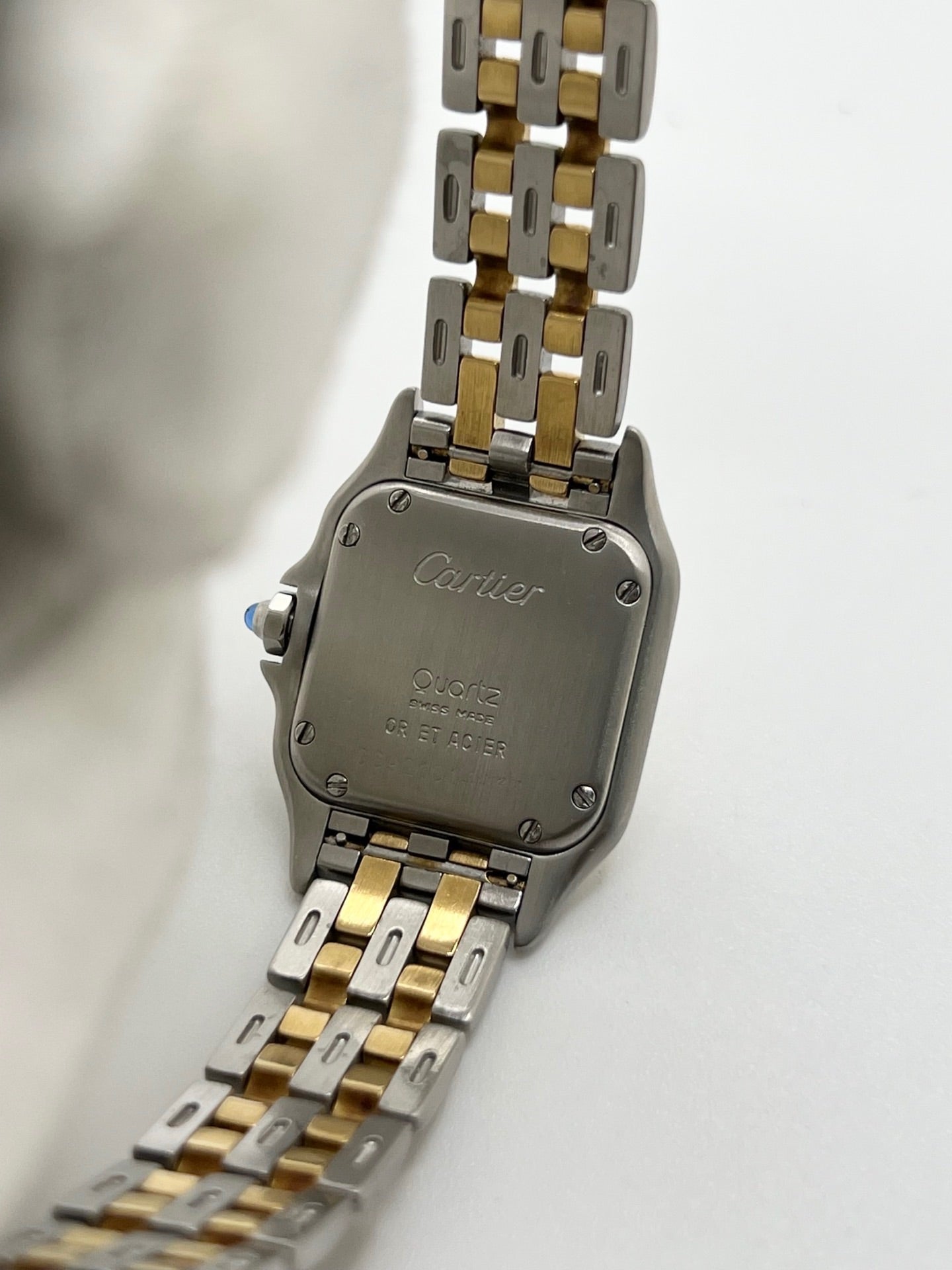 Montre Cartier Panthère référence 66921 pour femme en or jaune et acier, fabriquée en 1985 et équipée d'un mouvement quartz Swiss movement. Son boîtier rectangulaire de 22 x 30 mm est sublimé par une lunette en or jaune, un cadran blanc à chiffres romains et un verre saphir. Cette montre Cartier Panthère bicolore dispose d'un bracelet en or et acier avec boucle déployante. Vendue avec son coffret et ses papiers d'origine, elle est en très bon état et révisée en interne.
