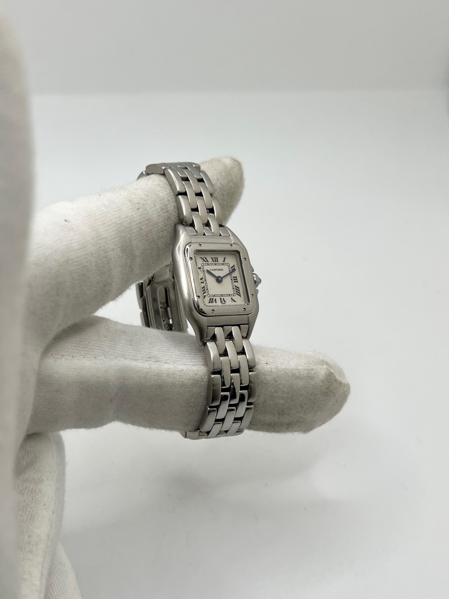 Cartier Panthère référence 1320 en acier avec boîtier de 22 mm, cadran blanc à chiffres romains et mouvement à quartz. Cette montre femme est équipée d'un bracelet en acier avec boucle déployante double pli et d'un verre saphir. Modèle d'occasion en très bon état, révisé par le fabricant en 2026, livré avec son coffret et ses papiers d'origine.
